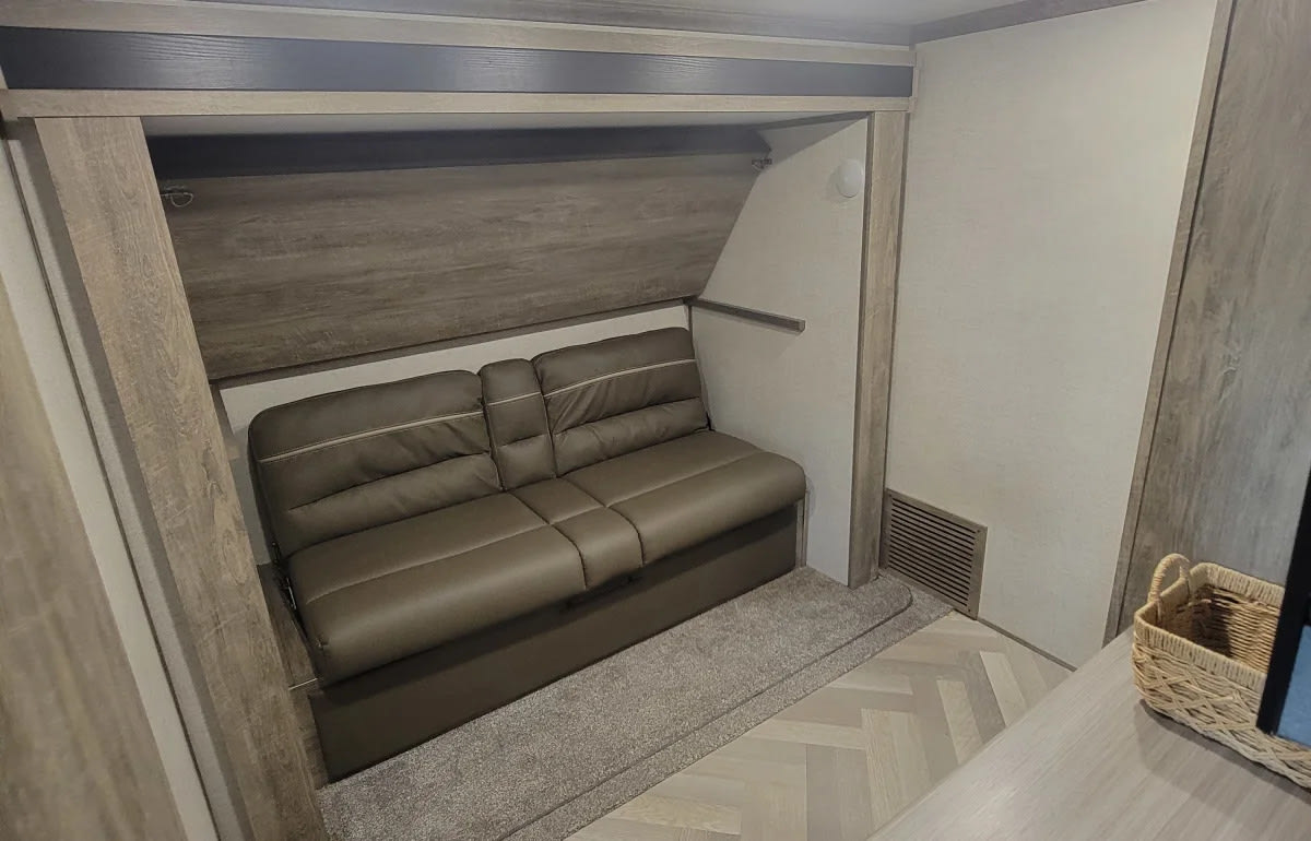 Cozy RV rental interior with a brown convertible sofa/bunk bed setup, ideal for compact travel living.. Forest River Wildwood Heritage Glen 2021