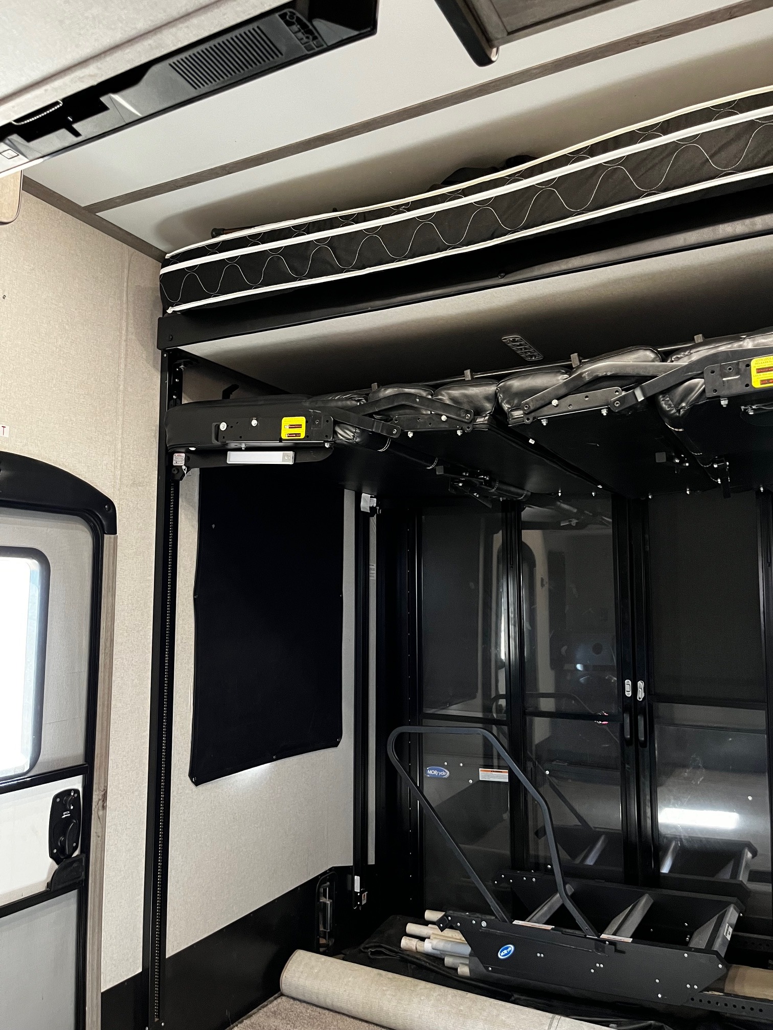RV rental toy hauler interior. Upper bunk bed, lower bed folded up, and rear ramp entry system visible.. Keystone Raptor 2020