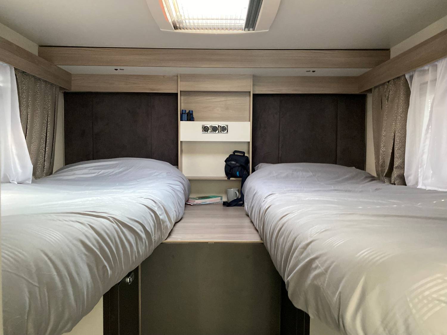 RV rental interior: Two cozy twin beds with light grey bedding and a central nightstand, offering a comfortable sleeping area.. Swift Voyager 485 2024