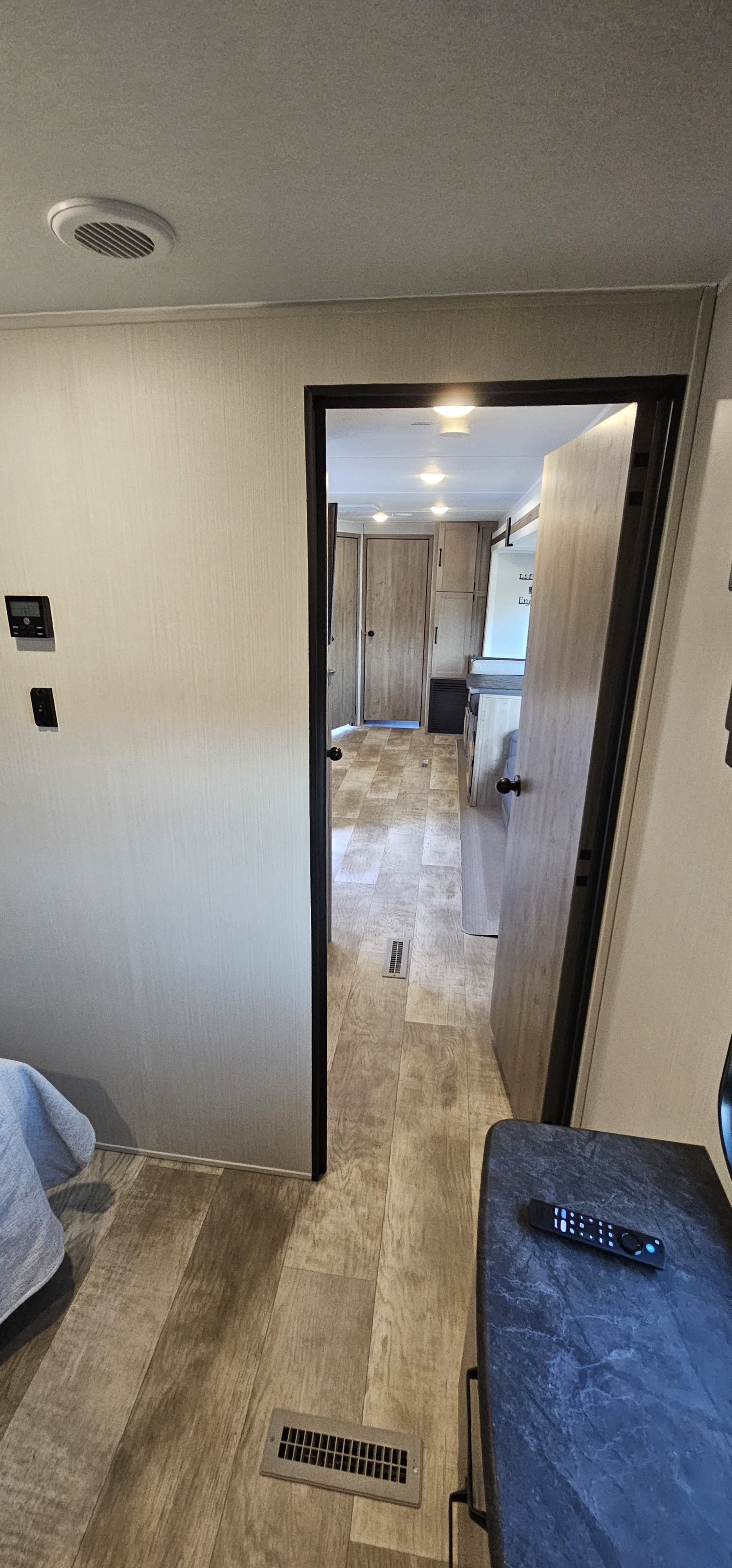 RV rental interior: A bright, modern hallway extends from a room, featuring wood-look flooring, ceiling lights, and wall controls.. Forest River Puma 2025