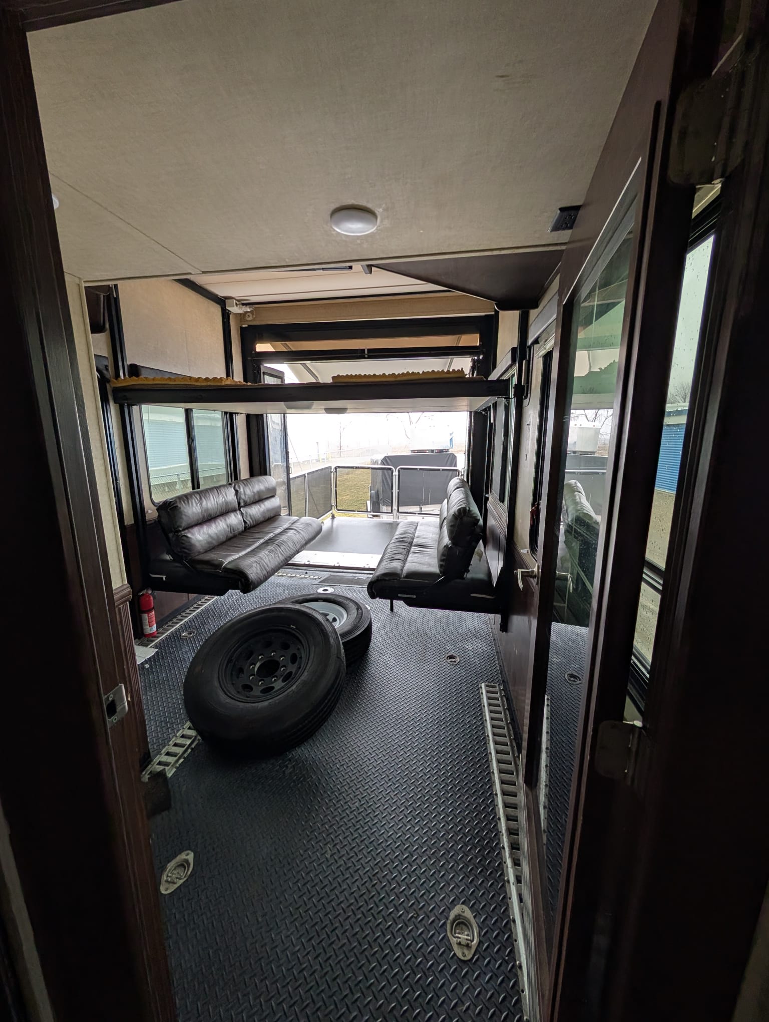 Spacious RV rental toy hauler interior. Features include convertible sofas, an upper bunk, diamond plate floor, and open rear ramp.. Keystone Cyclone 4500 2015