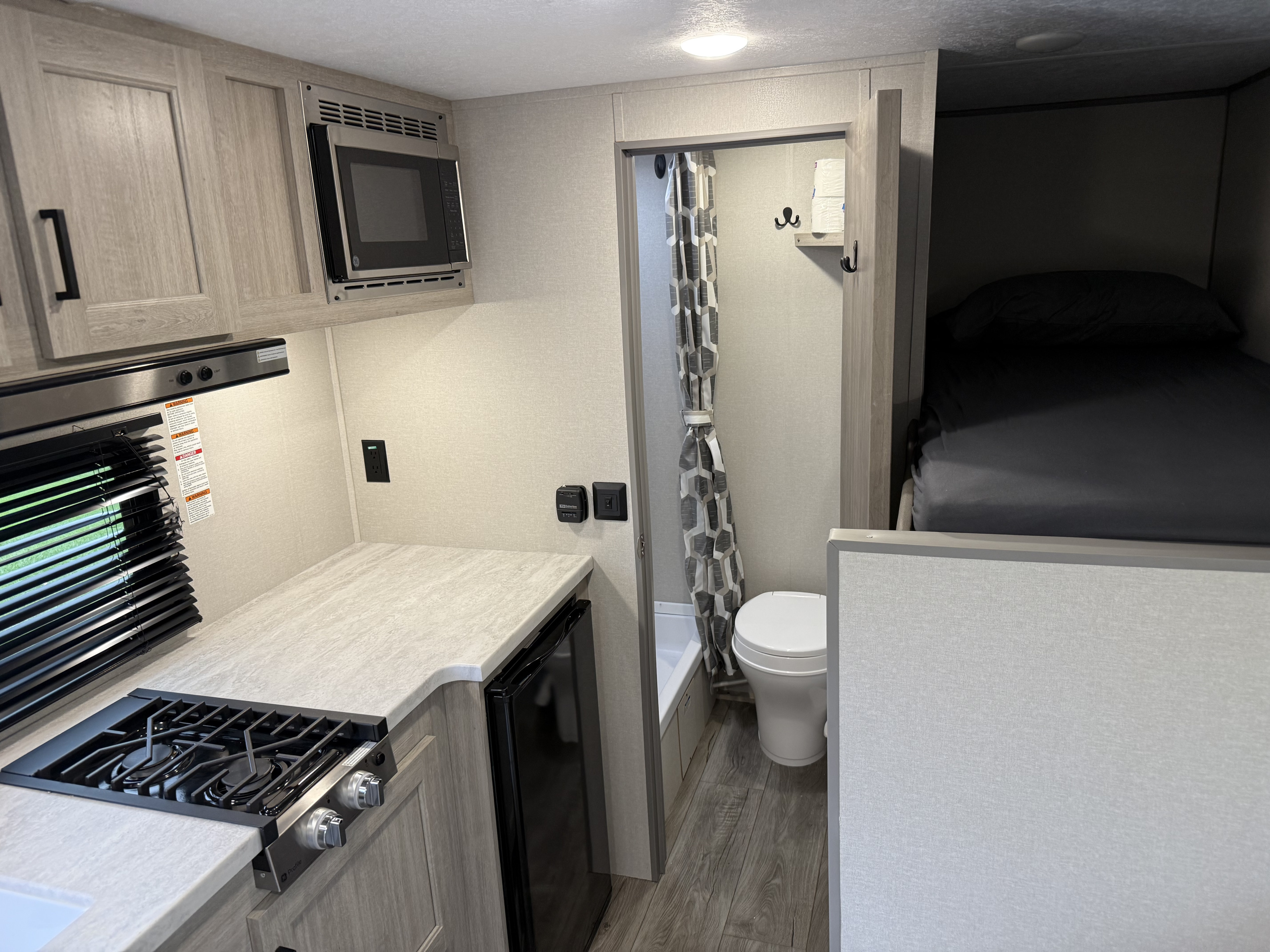 RV rental interior: Kitchenette with stove, microwave, fridge. Bathroom with toilet, shower. Bunk bed area.. Forest River Coachmen Catalina Summit 2024