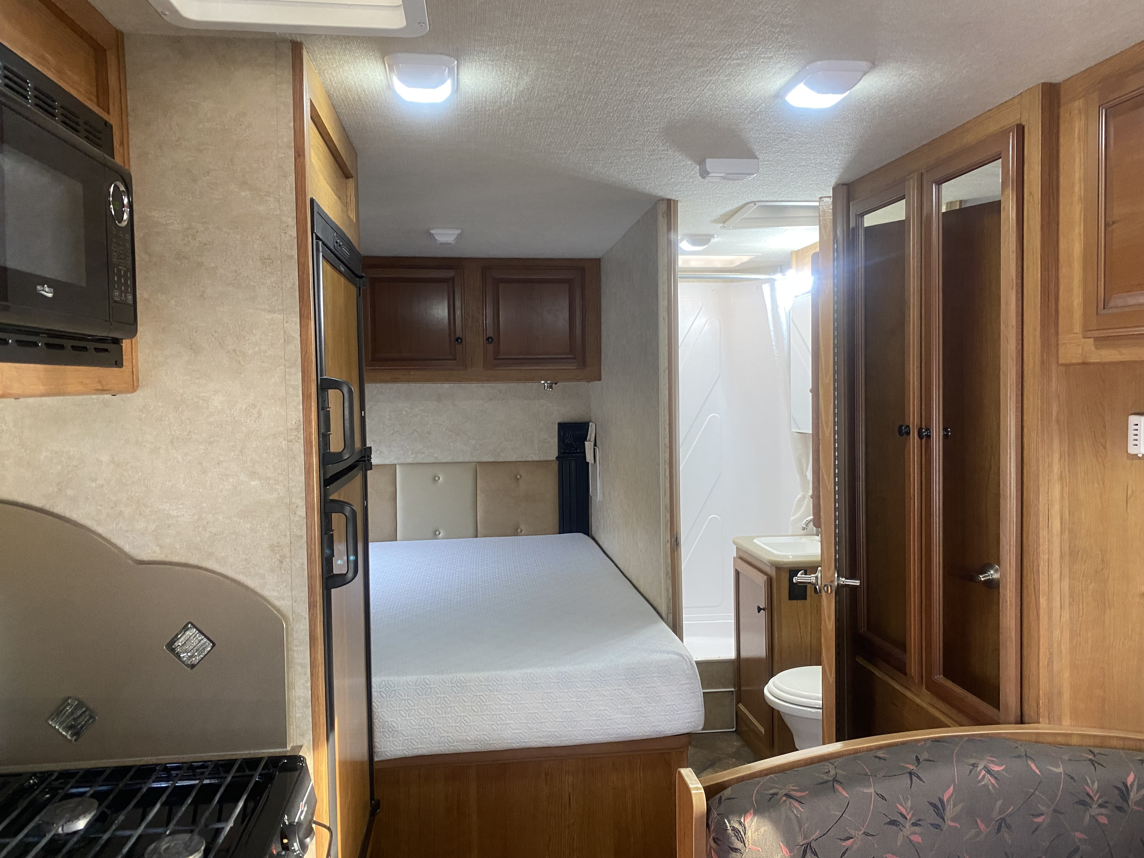 Clean RV rental interior. View of kitchen (microwave, fridge), cozy bed, & compact bathroom. Ready for your next adventure.. Tioga Montara 2016