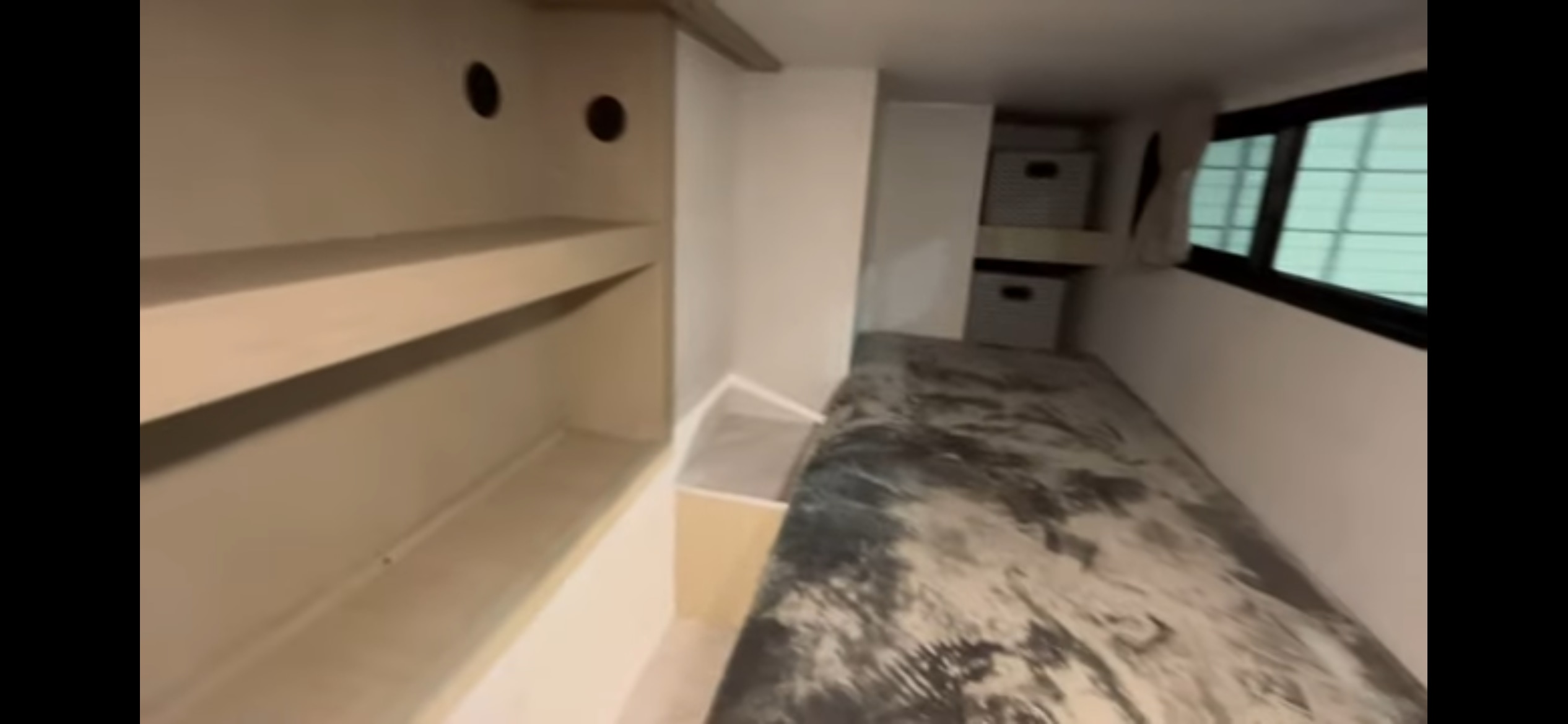 RV rental interior: a compact bedroom features a bed, built-in shelves, and storage bins, with a window visible.. Forest River Salem 2024