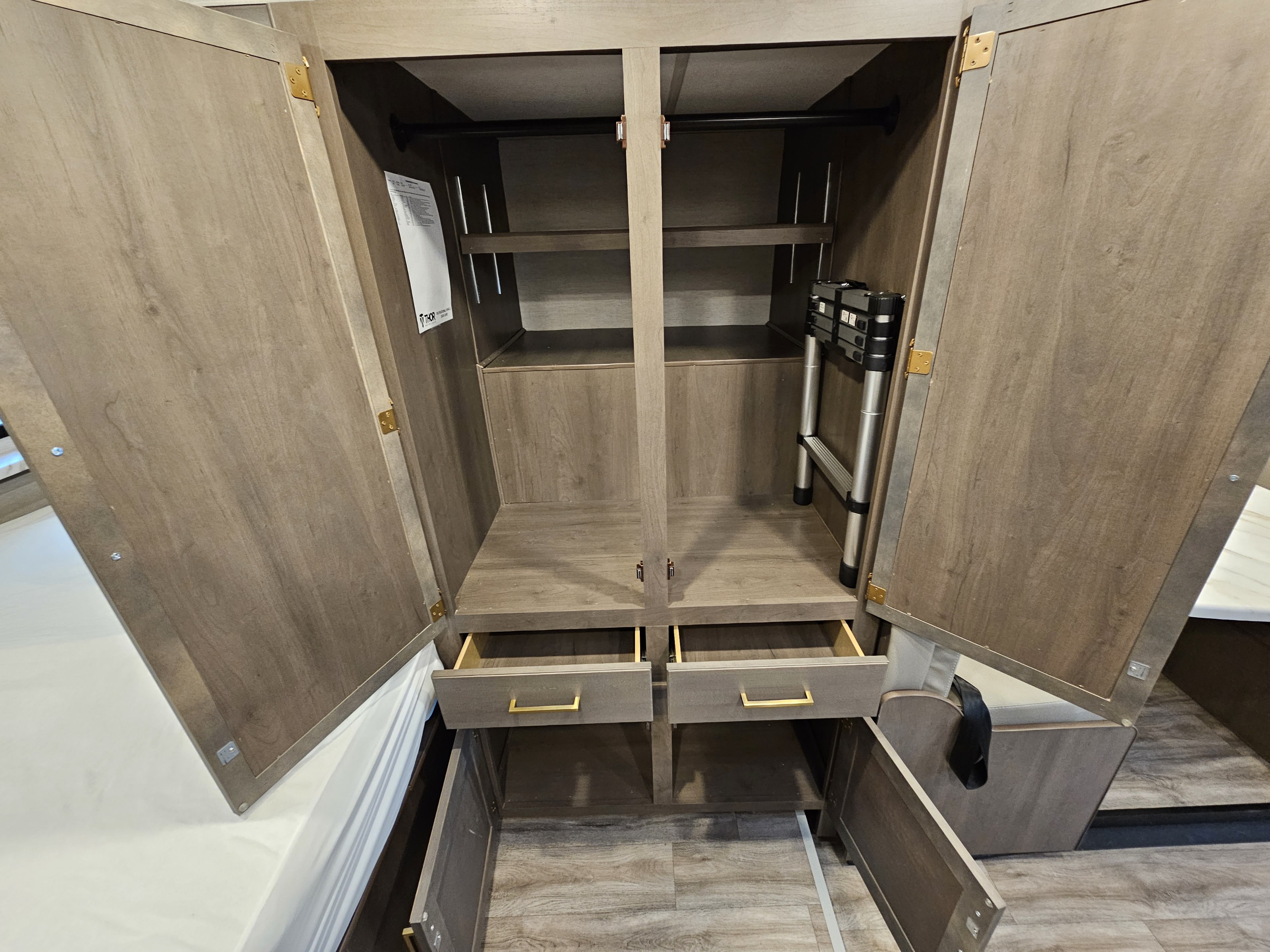 This RV rental's organized wardrobe features a hanging rod, adjustable shelves, two drawers, and a compact stored ladder.. Thor Motor Coach Four Winds 2026