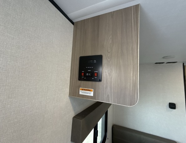 RV rental interior: A black control panel on a light wood cabinet for water tanks/battery status. Perfect for an RV adventure.. Keystone Coleman 17R 2025