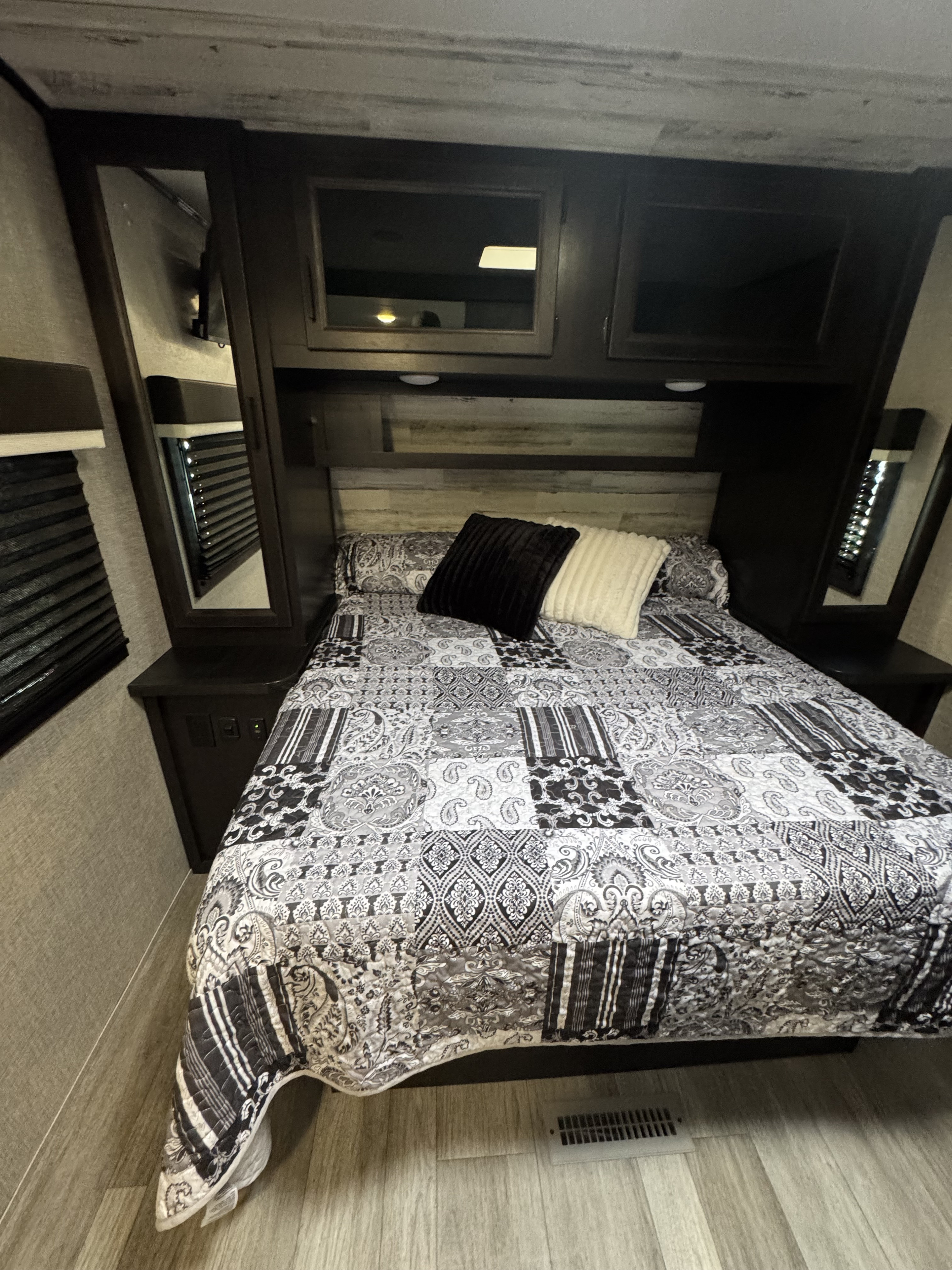 Comfortable RV rental bedroom with a stylish black and white quilt, ample storage, and built-in mirrors, perfect for travelers.. Jayco Jay Feather 2022