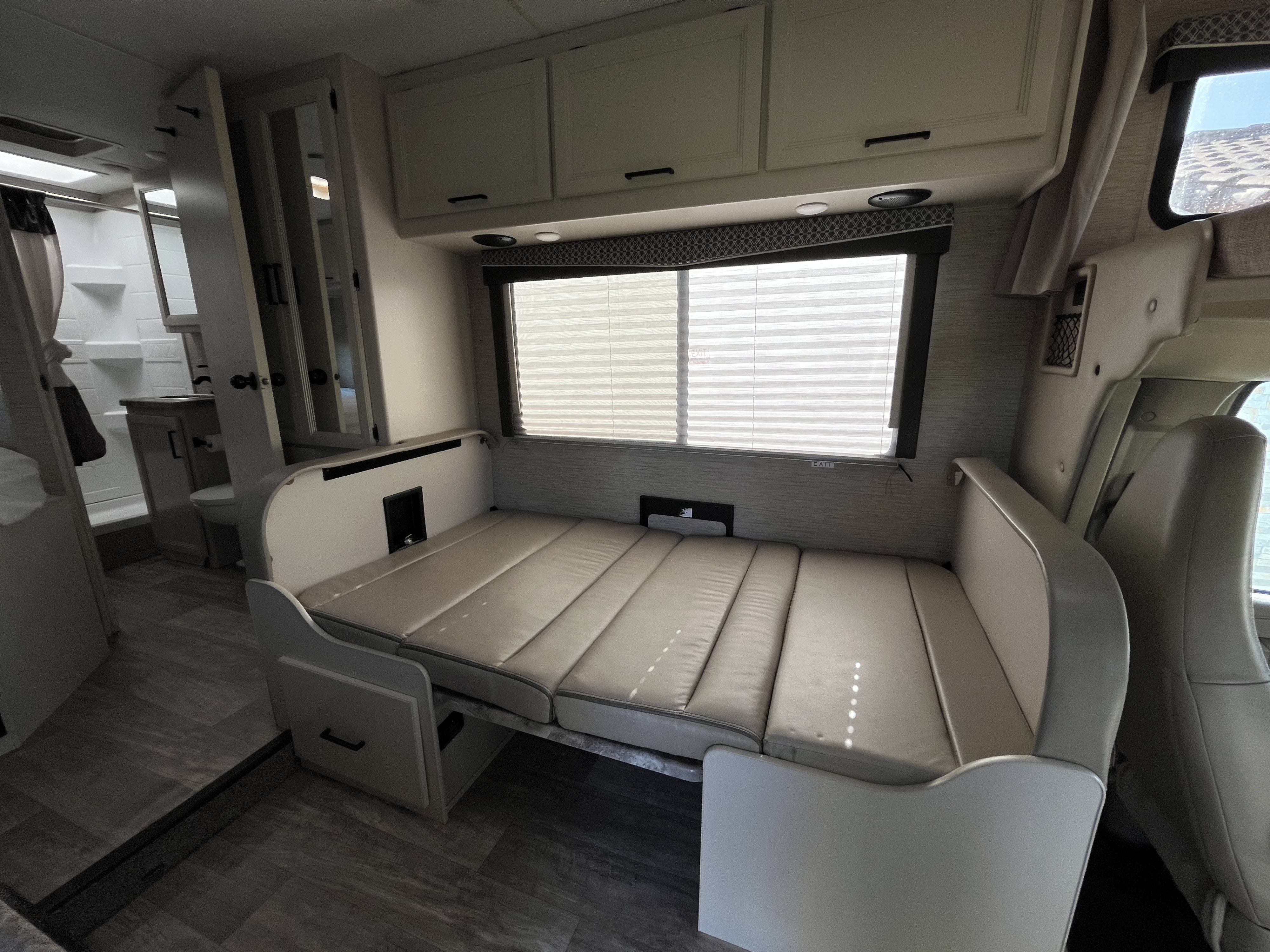 RV rental interior shows convertible dinette/bed, overhead cabinets, bathroom, and front seats.. Thor Chateau 2023