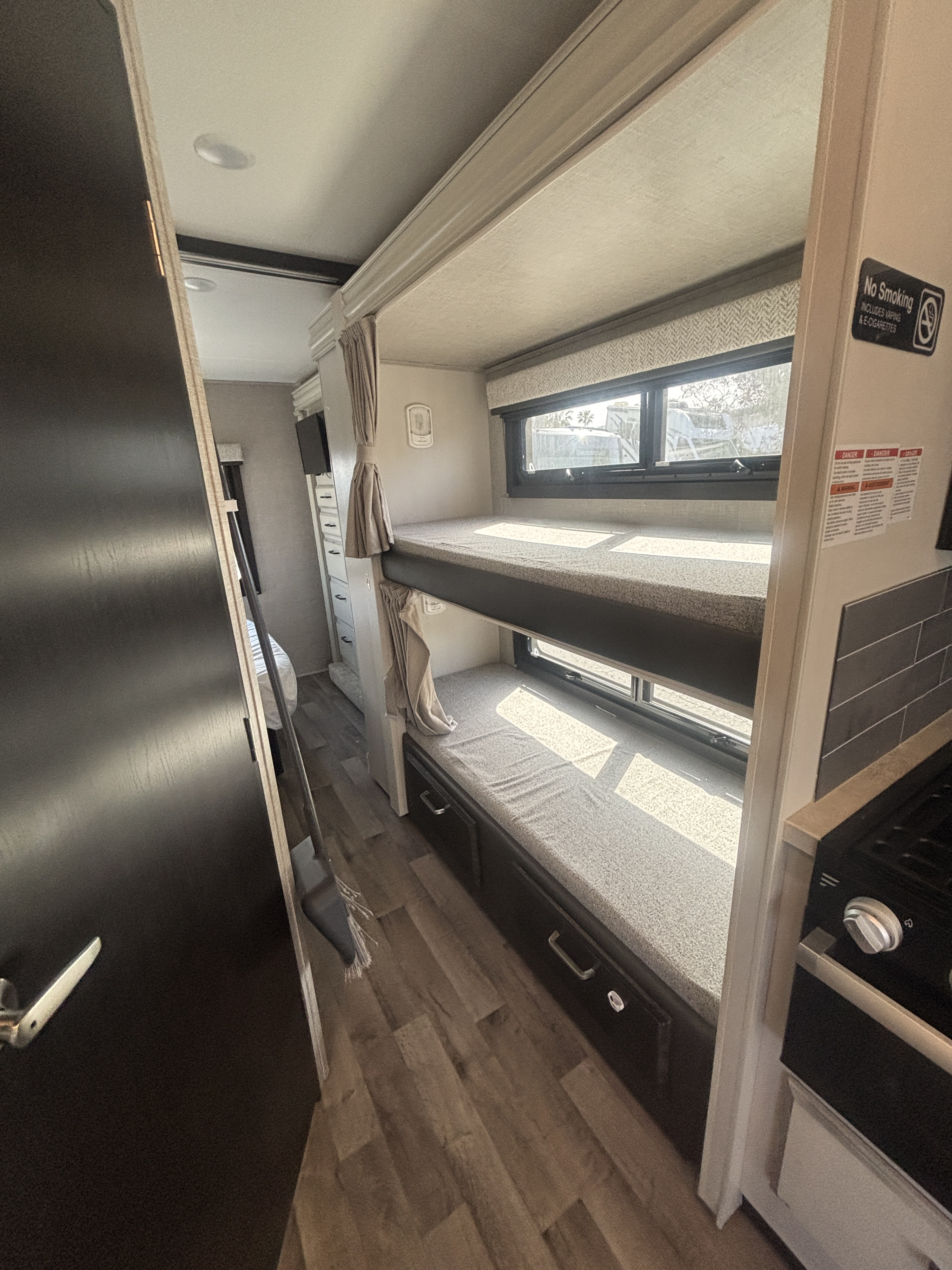 Bright RV rental interior shows bunk beds, a compact kitchen, and bedroom access. Ideal for travel and camping adventures.. Entegra Coach Odyssey 2023