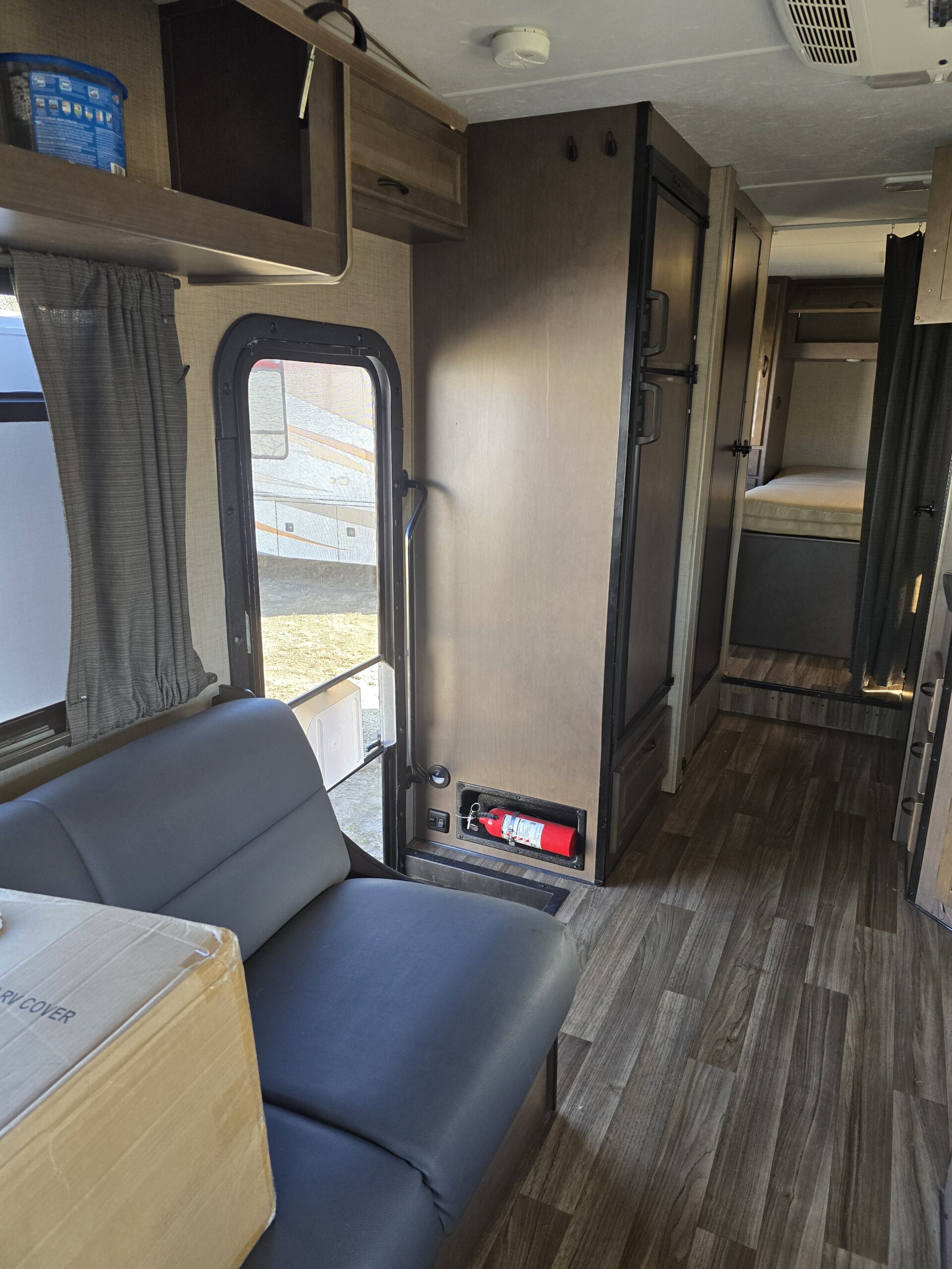 Inside an RV rental: a cozy living area with seating, kitchen appliances, rear bunk bed, and safety gear. Wood-look flooring throughout.. Thor Majestic 2019