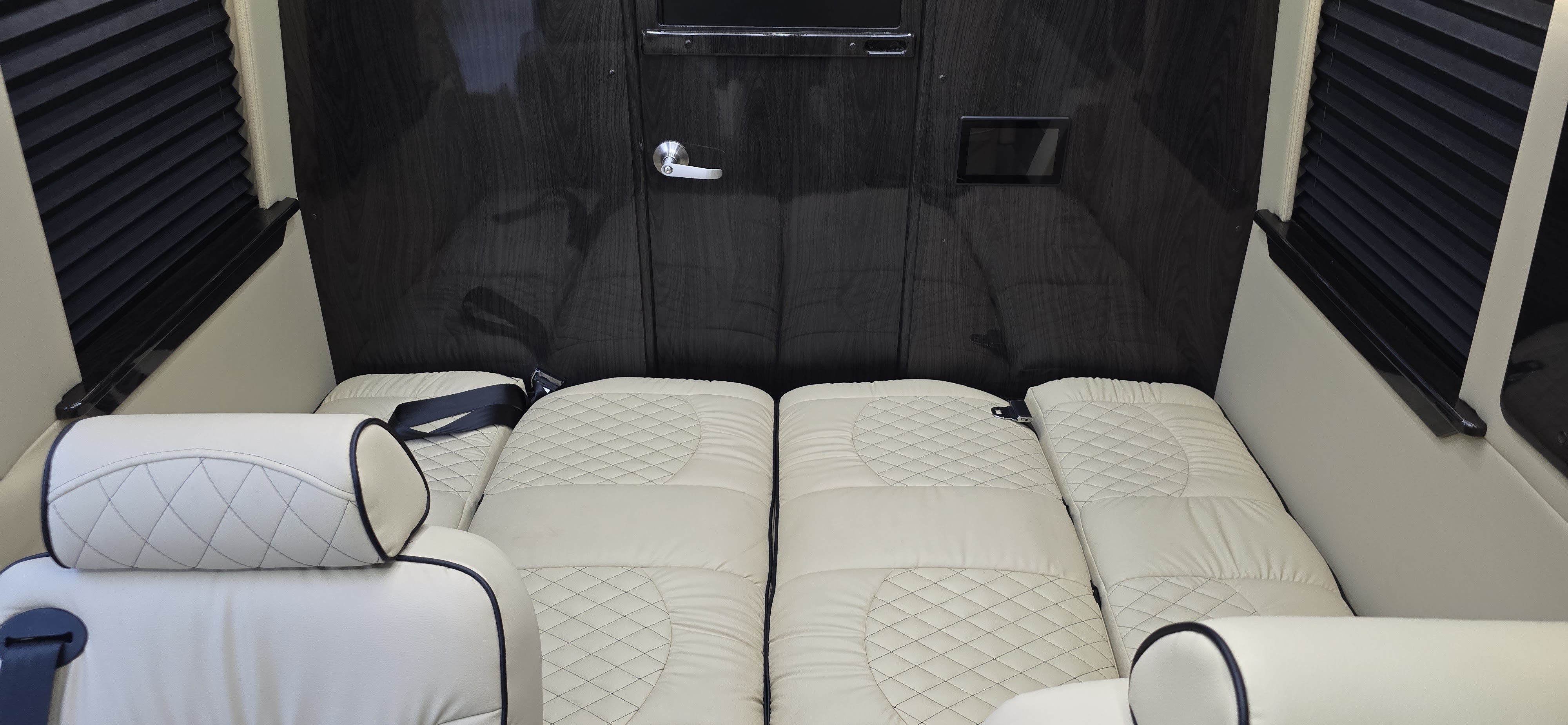 Plush RV rental interior with cream quilted leather seats converted to beds, offering luxurious travel comfort.. Ultimate Toys Ultimate Cruiser 2023