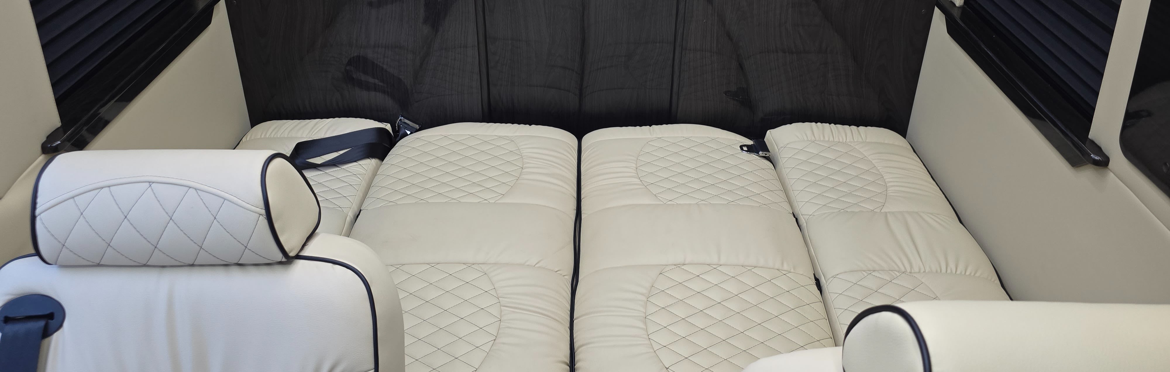 Spacious RV rental interior featuring plush cream quilted leather seating, convertible to a comfortable bed for travel.. Ultimate Toys Ultimate Cruiser 2023