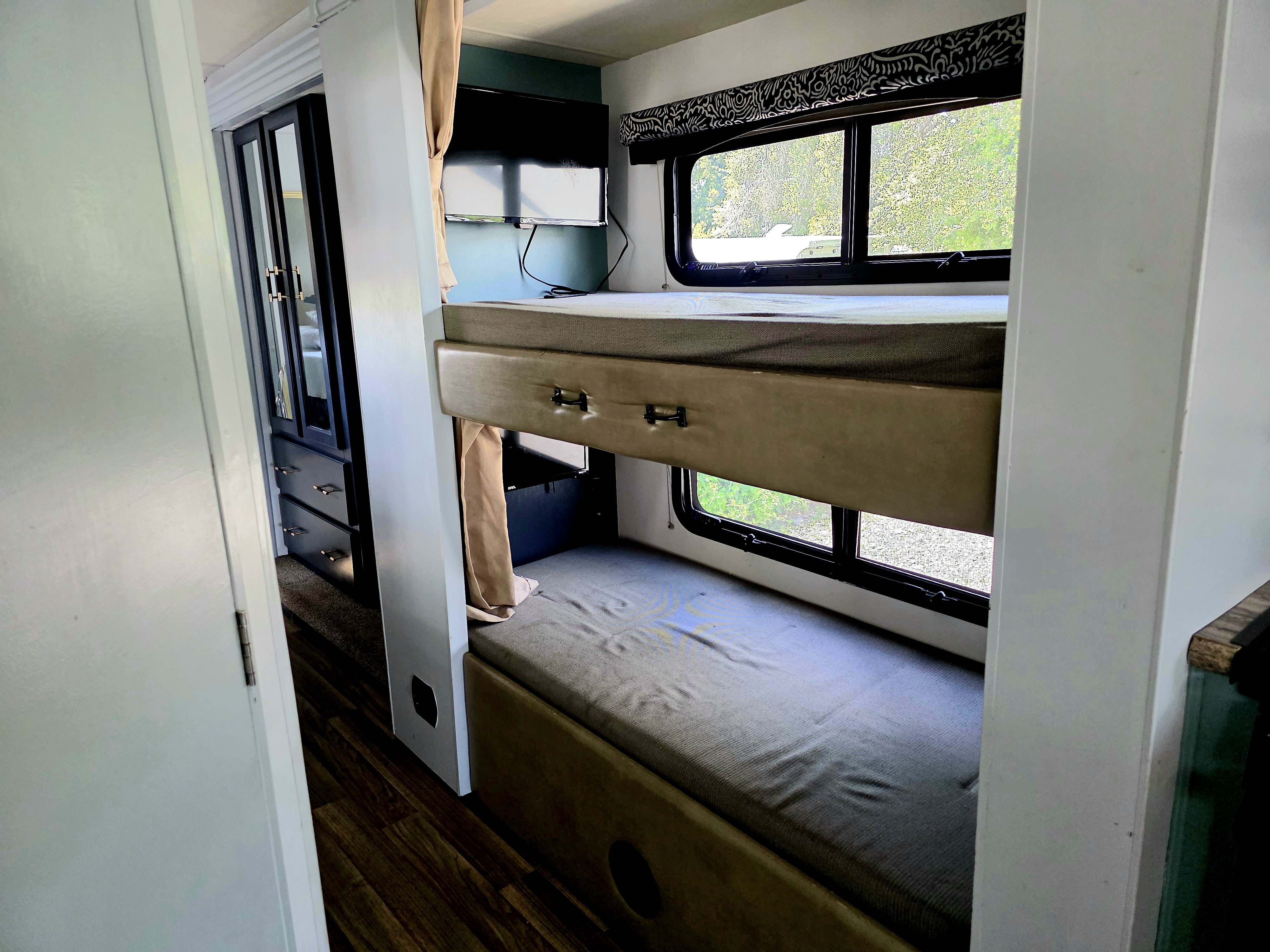 Experience comfort in this RV rental's bunk bed area with TV, storage, and a view of nature outside.. Thor Motor Coach A.C.E 2018