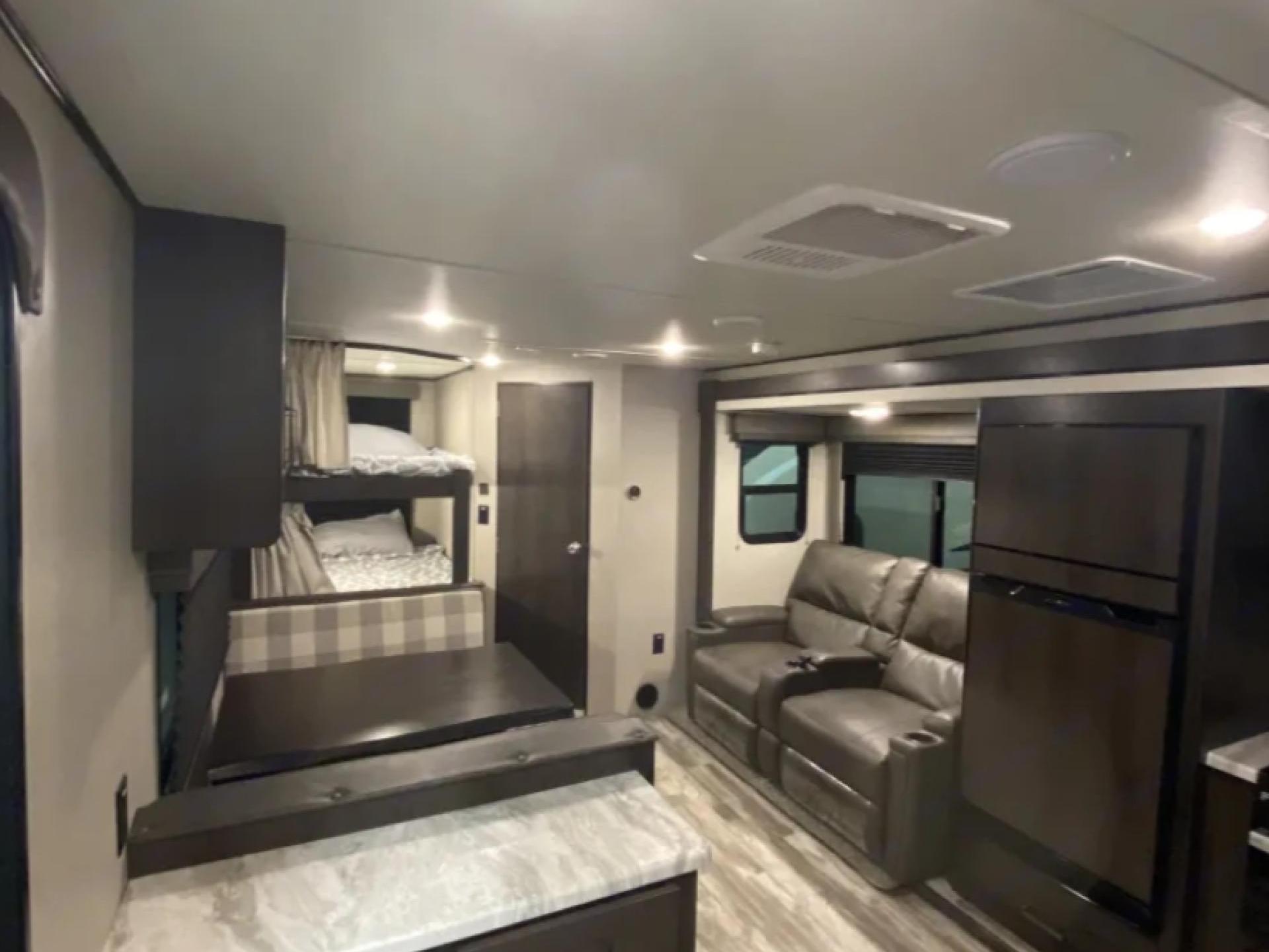 Inside this modern RV rental: bunk beds, a dinette, comfy sofa, and full-size fridge. Ideal for family adventures.. Grand Design Transcend Xplor 2021