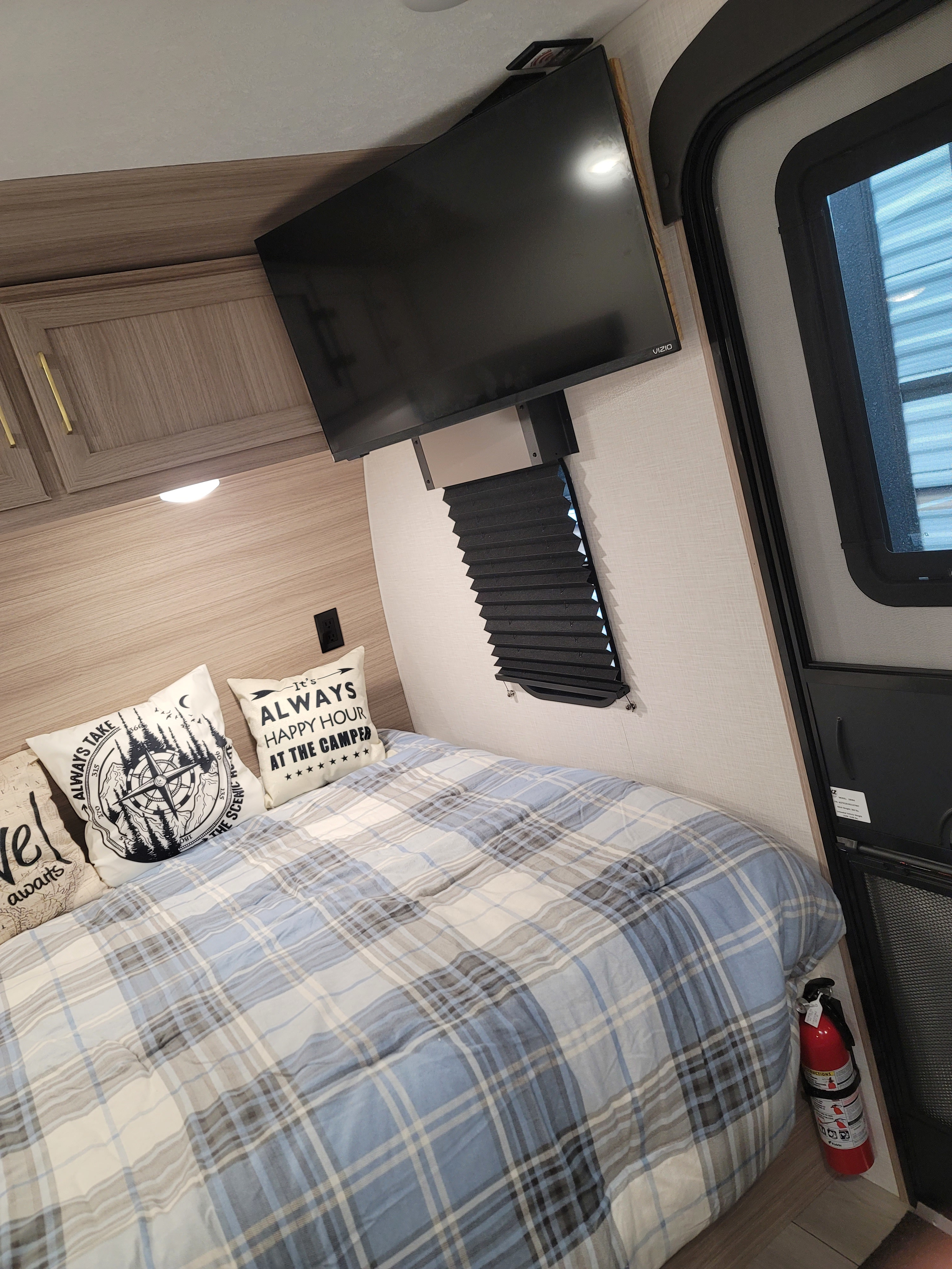 Inside a cozy RV rental bedroom: plaid bedding, TV, decorative pillows, and a fire extinguisher for safety.. KZ KZ SPORTSMAN CLASSIC 180BH 2025