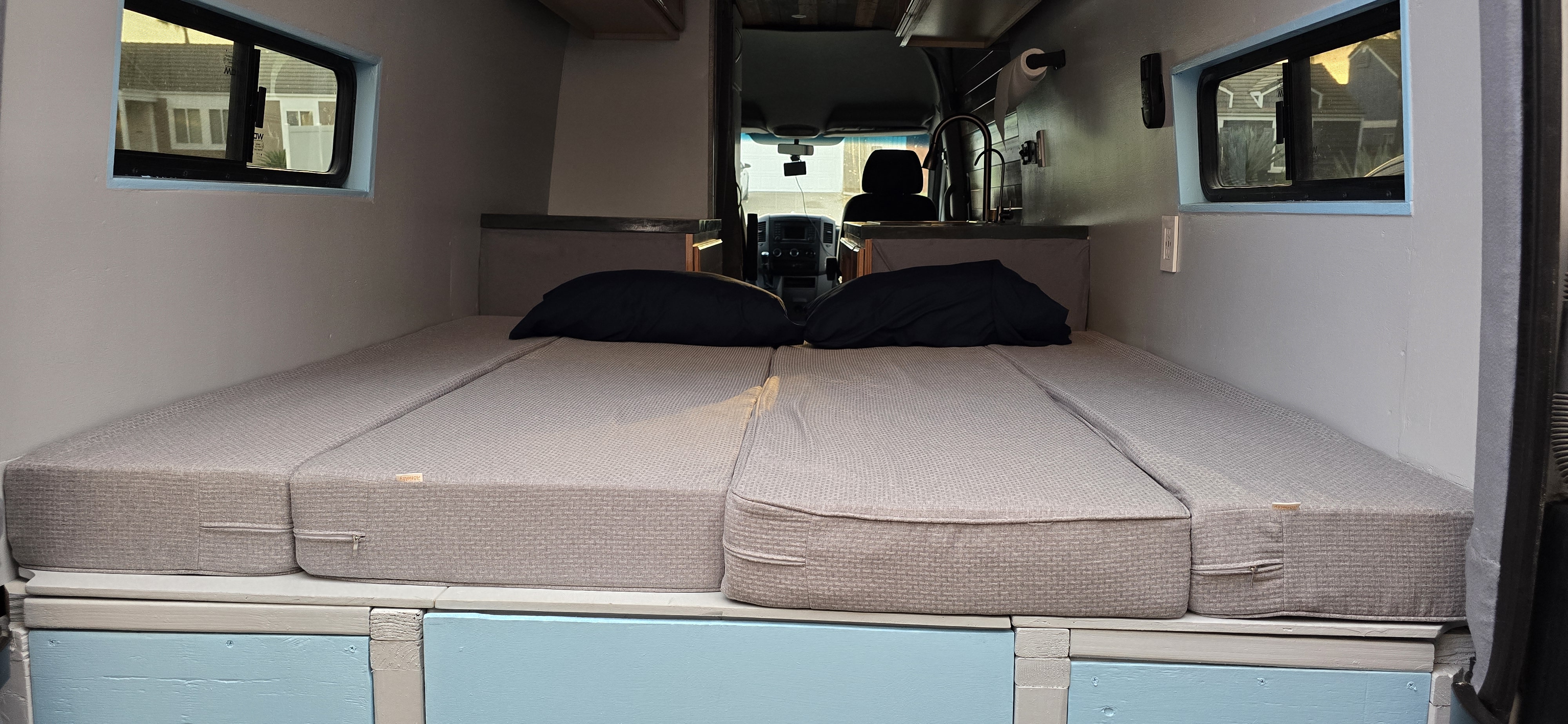 Comfy modular bed & kitchenette inside an RV rental camper van.. Mercedes Sprinter 2014