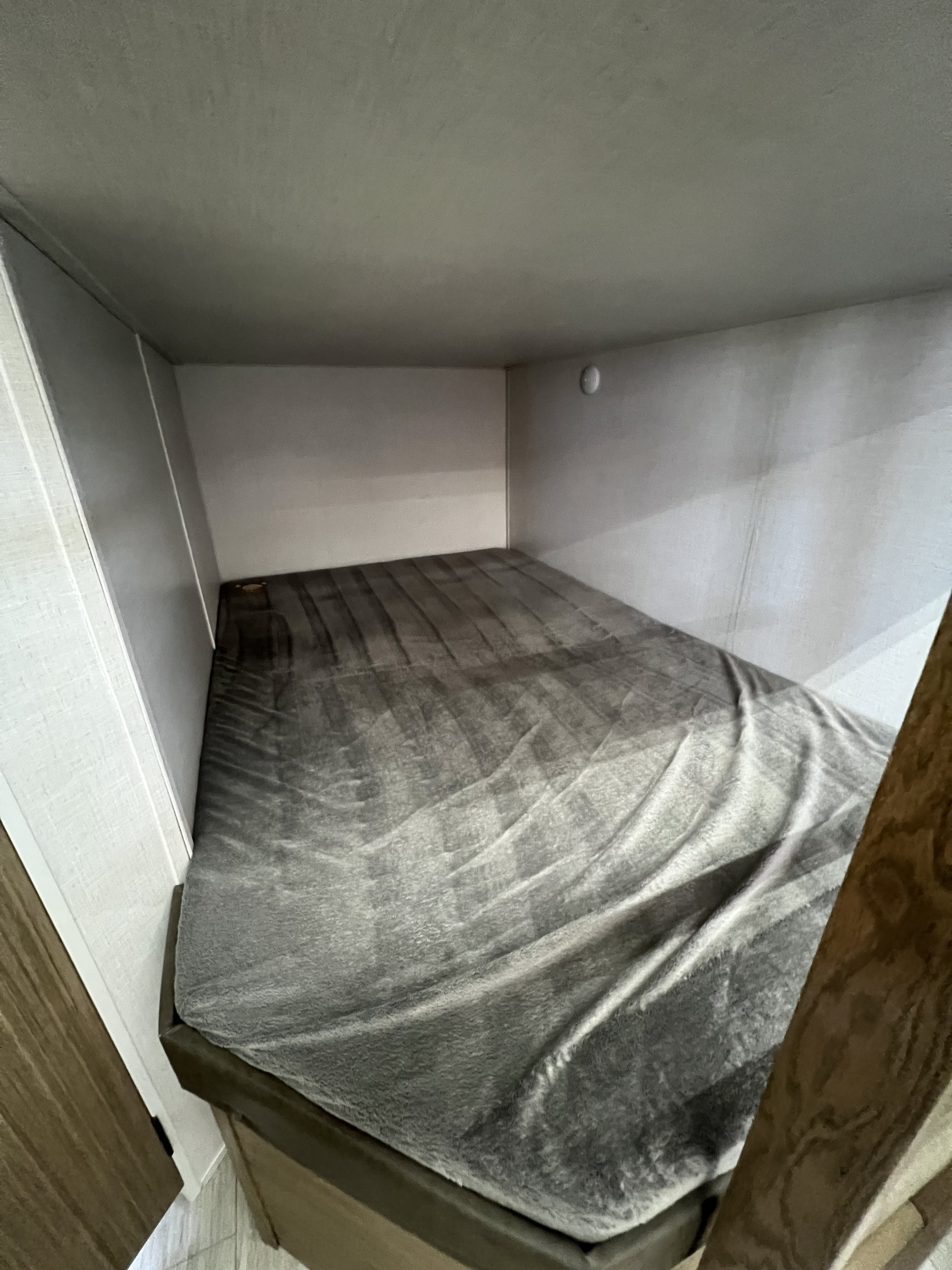 Cozy RV rental bunk bed with a soft grey blanket inside a compact sleeping area.. Forest River Salem Cruise Lite 2025
