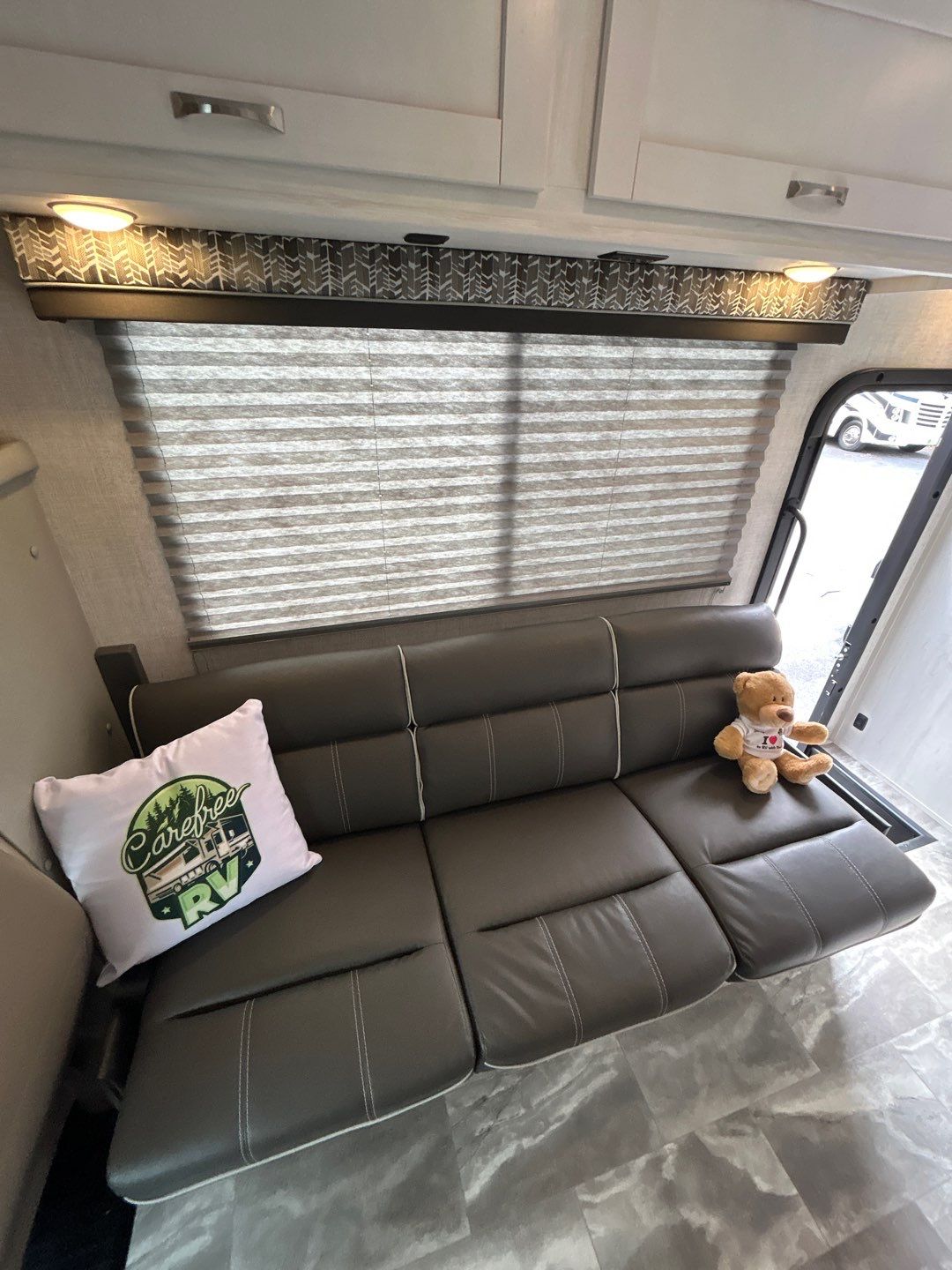 Cozy RV rental interior featuring a gray sofa bed, window blinds, and overhead lighting.. Gulf Stream Conquest 2022