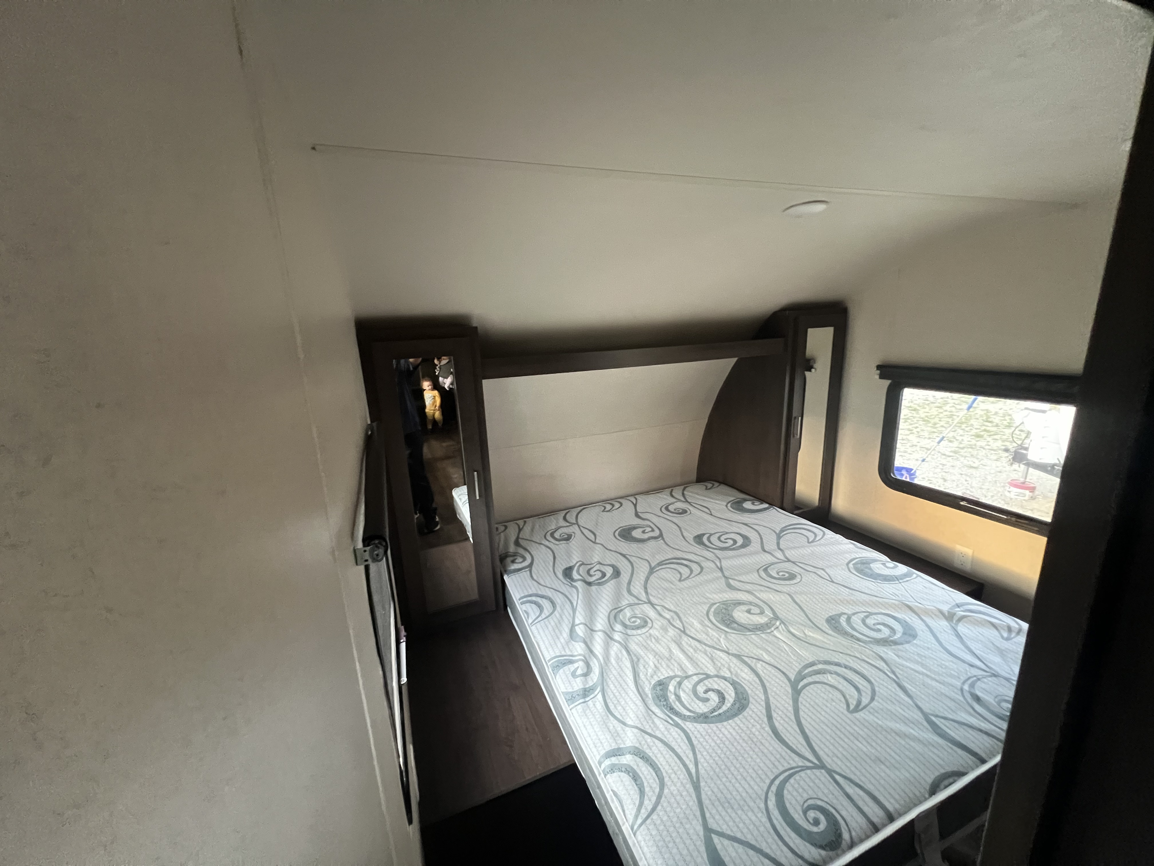 Cozy RV bedroom with patterned mattress, built-in storage, and window view. Great for your next rv rental!. FOREST RIVER Wildwood X-Lite 2018