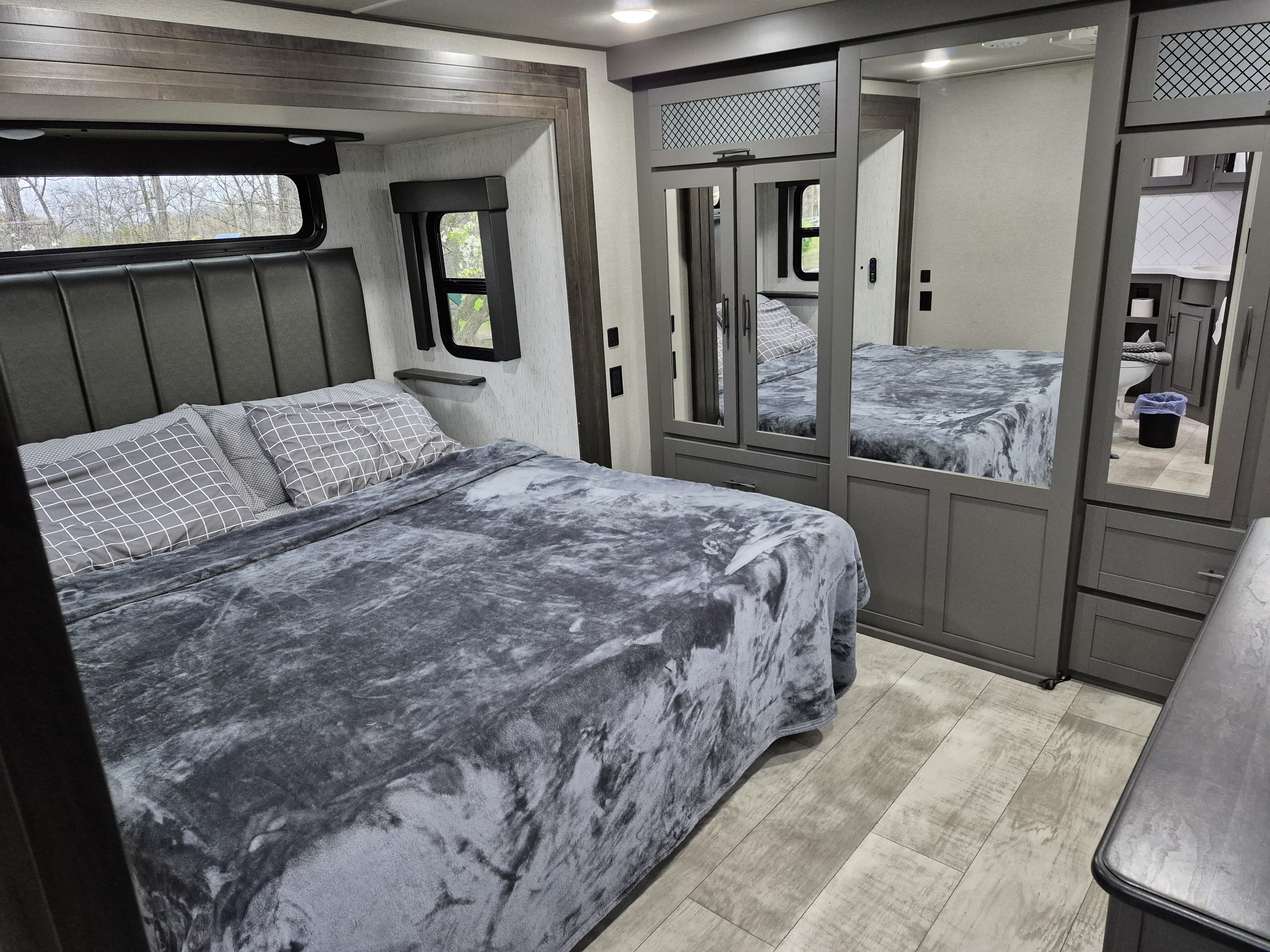 Spacious RV rental bedroom with a comfortable bed, mirrored closet, and a glimpse into the connected bathroom.. Grand Design Momentum 2022
