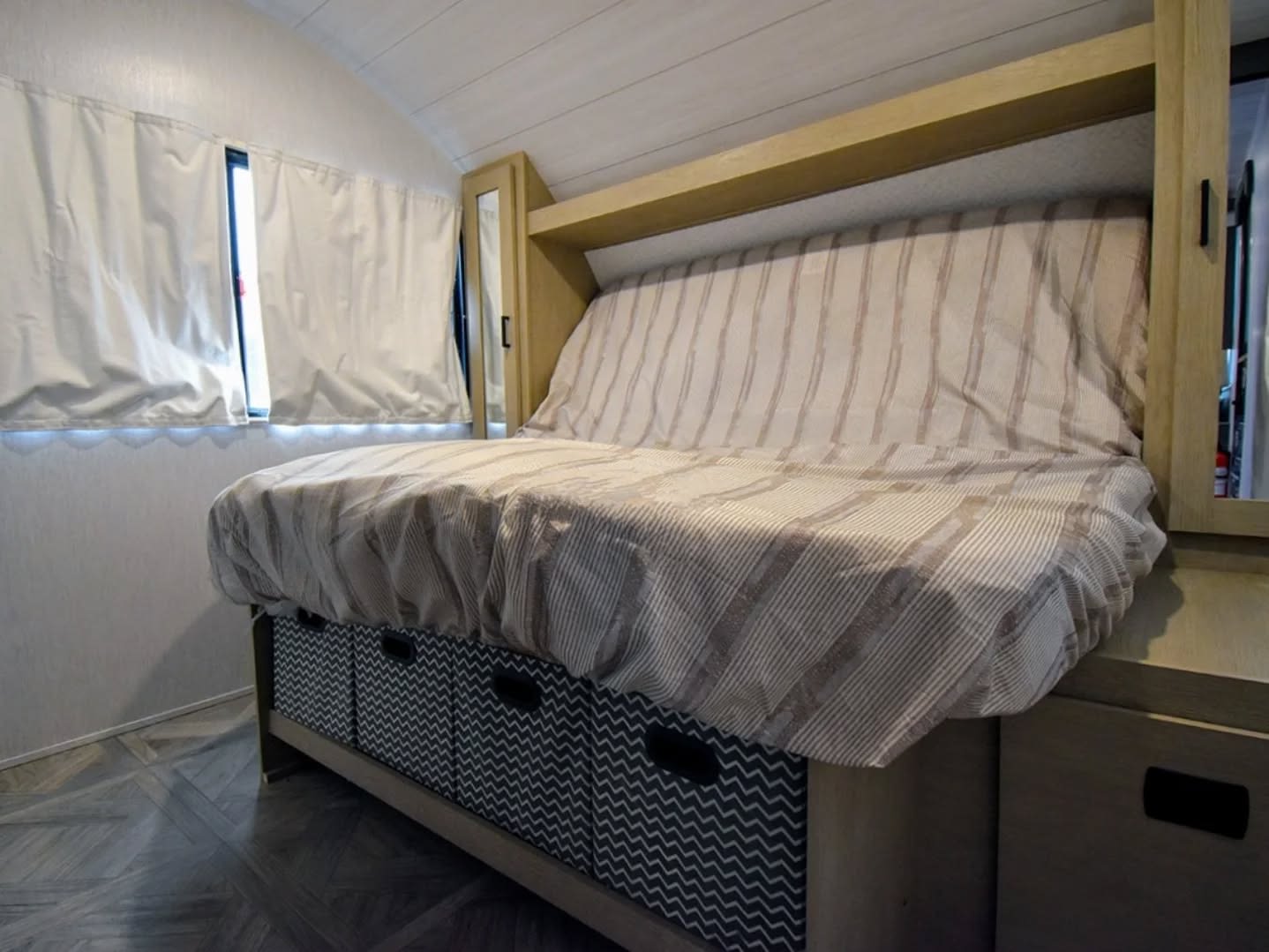 Cozy **RV rental** interior: a compact sofa-bed with striped bedding, under-bed storage, and window shades.. Forest River Salem Cruise Lite 2024