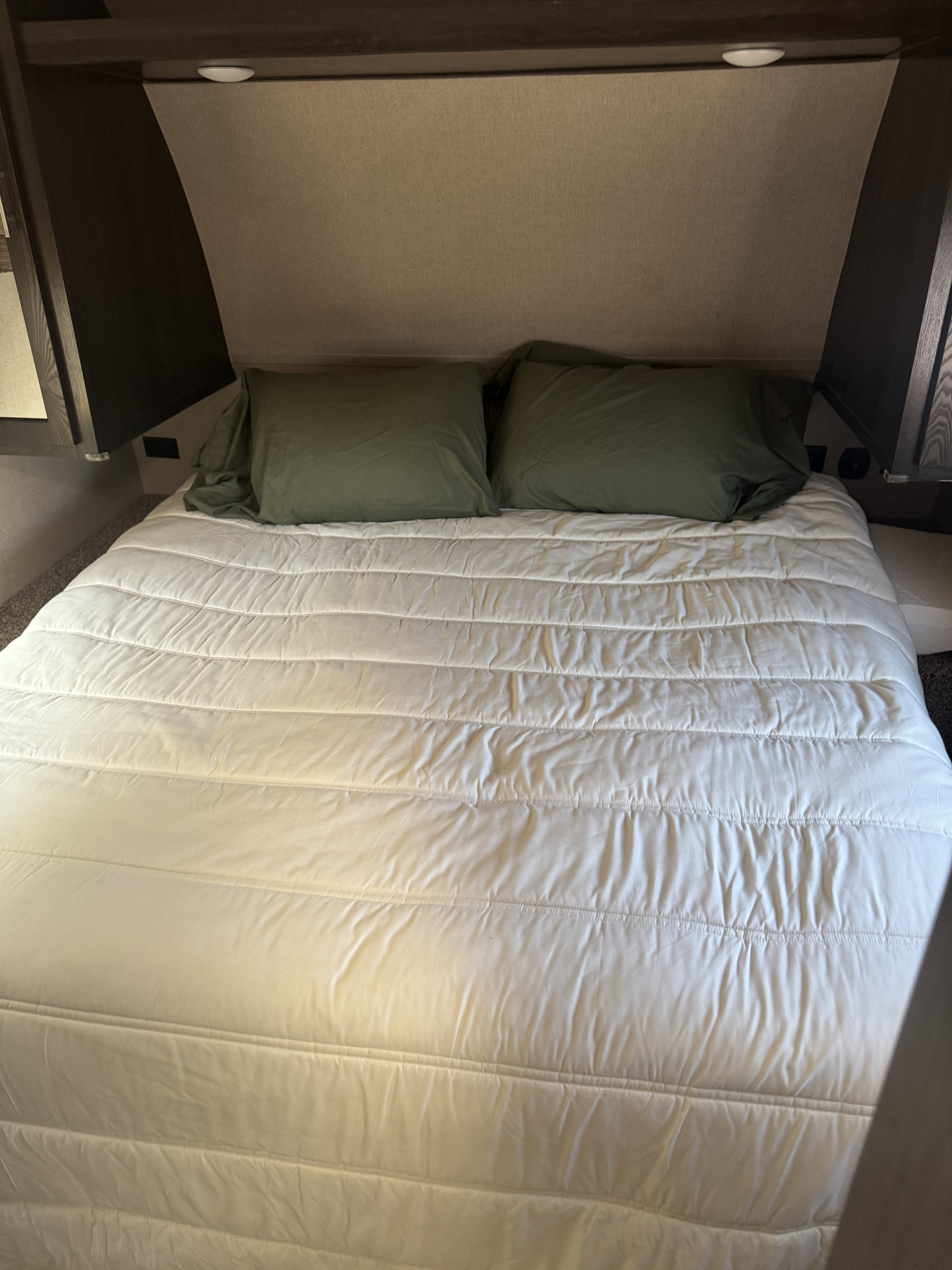 Inside an RV rental: A neat bed with a white quilted comforter and olive pillows, showcasing the cozy sleeping area.. Forest River Nitro Xlr 2017