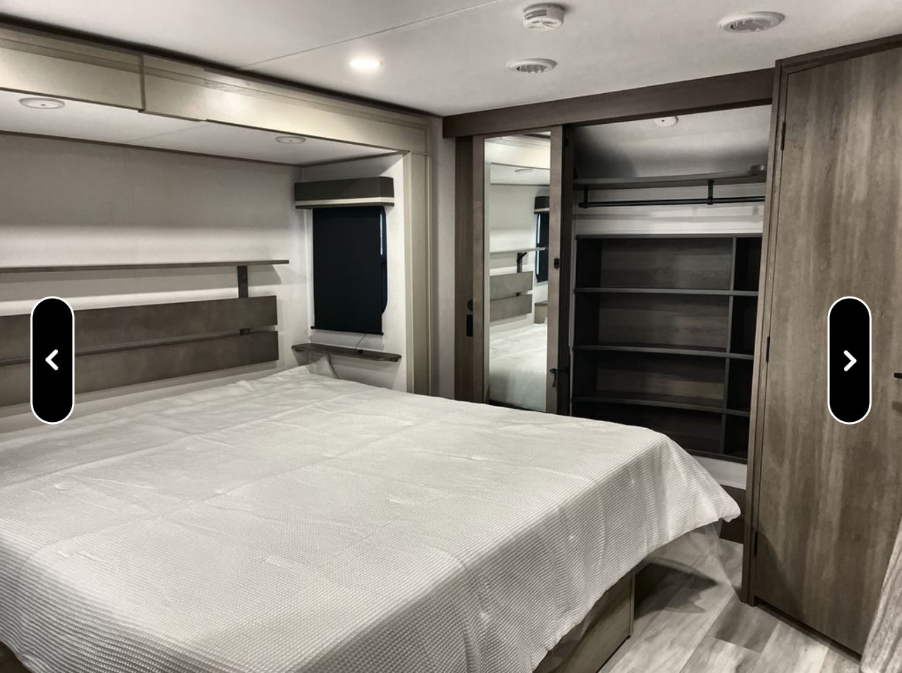 Cozy RV rental bedroom with a large bed, ample storage, and mirrored closet doors. Perfect for your next adventure.. Grand Design Influence 2024