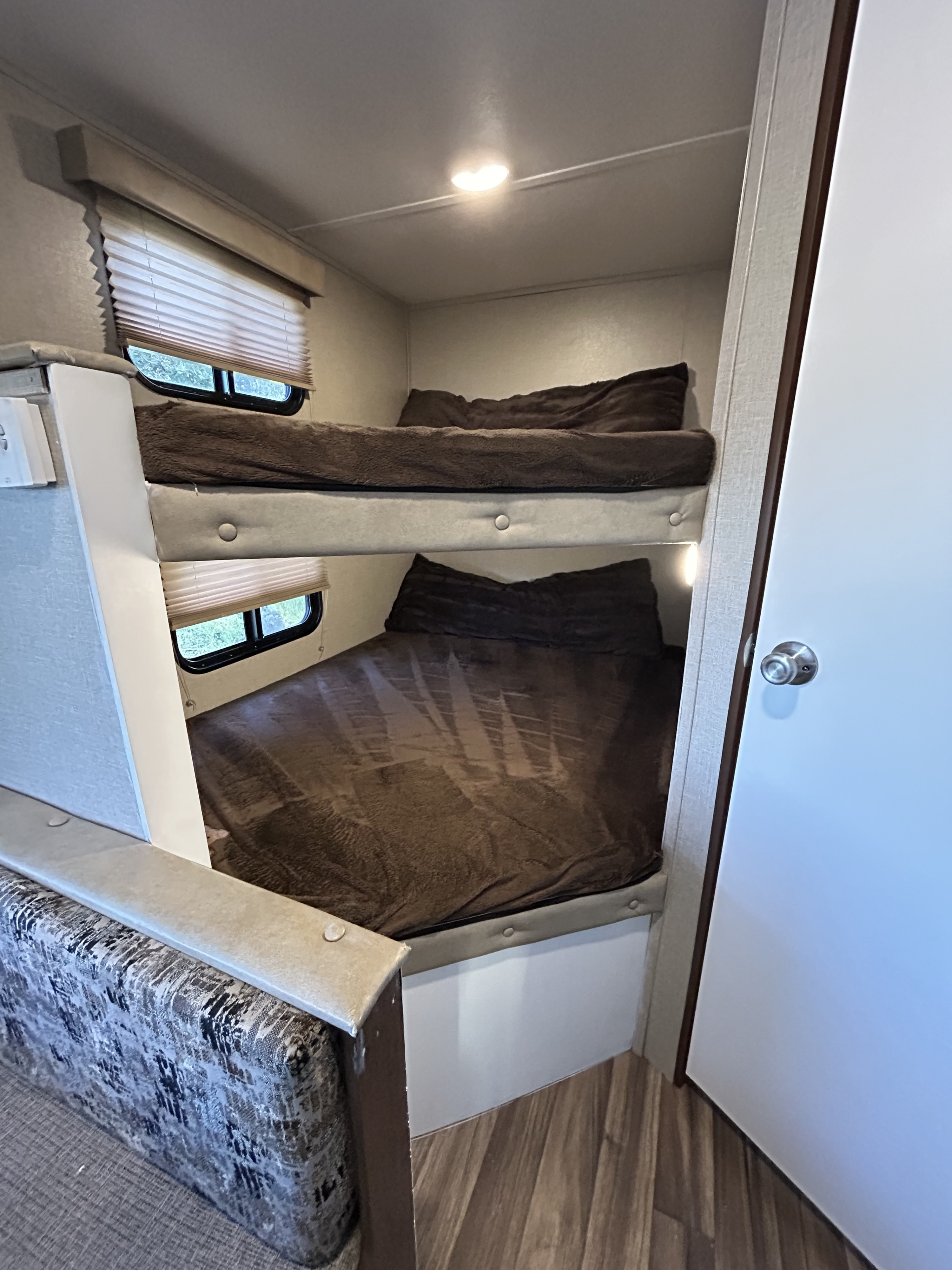 Inside a comfortable RV rental: two bunk beds with cozy brown bedding, windows, and light. Ideal compact sleeping.. Keystone Hideout 2018