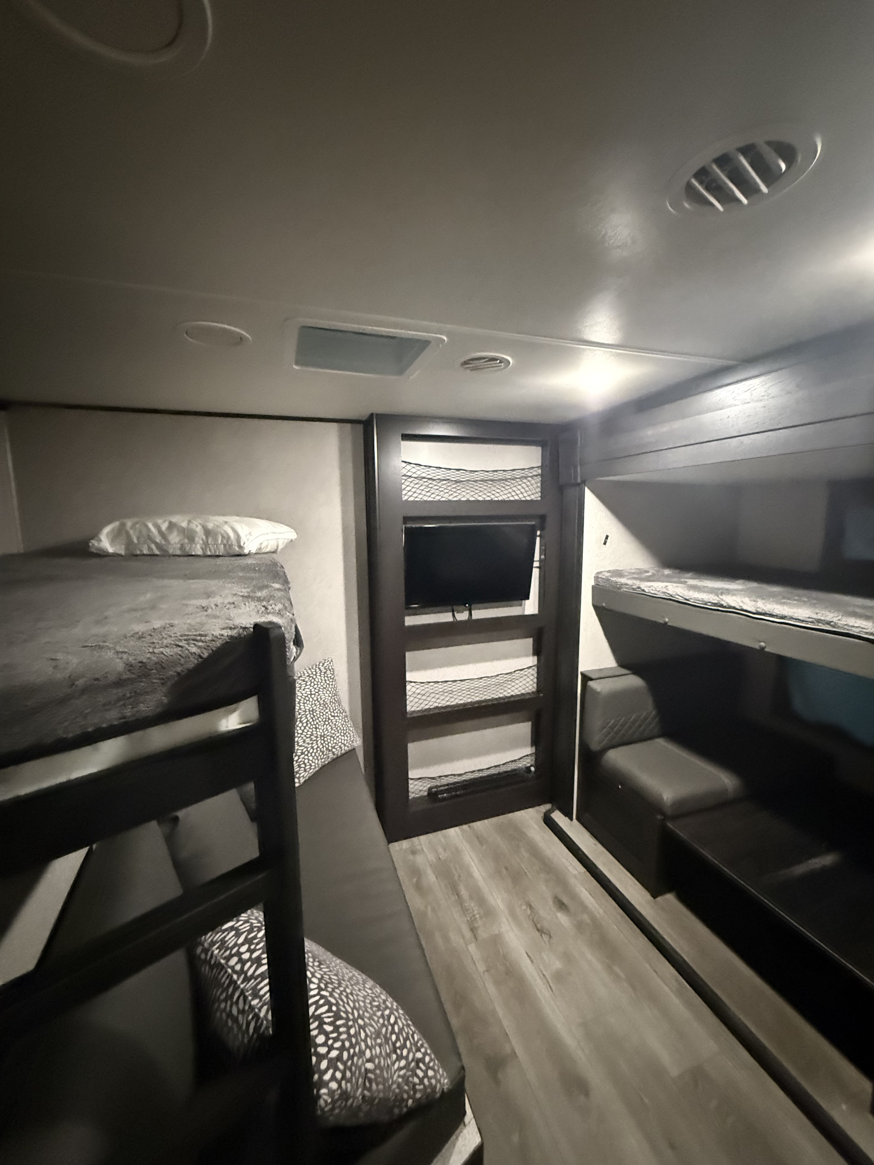 Inside a modern RV rental, featuring a bunkhouse with cozy beds, a TV, and convenient storage solutions.. Highland Ridge RV Open Range 2021