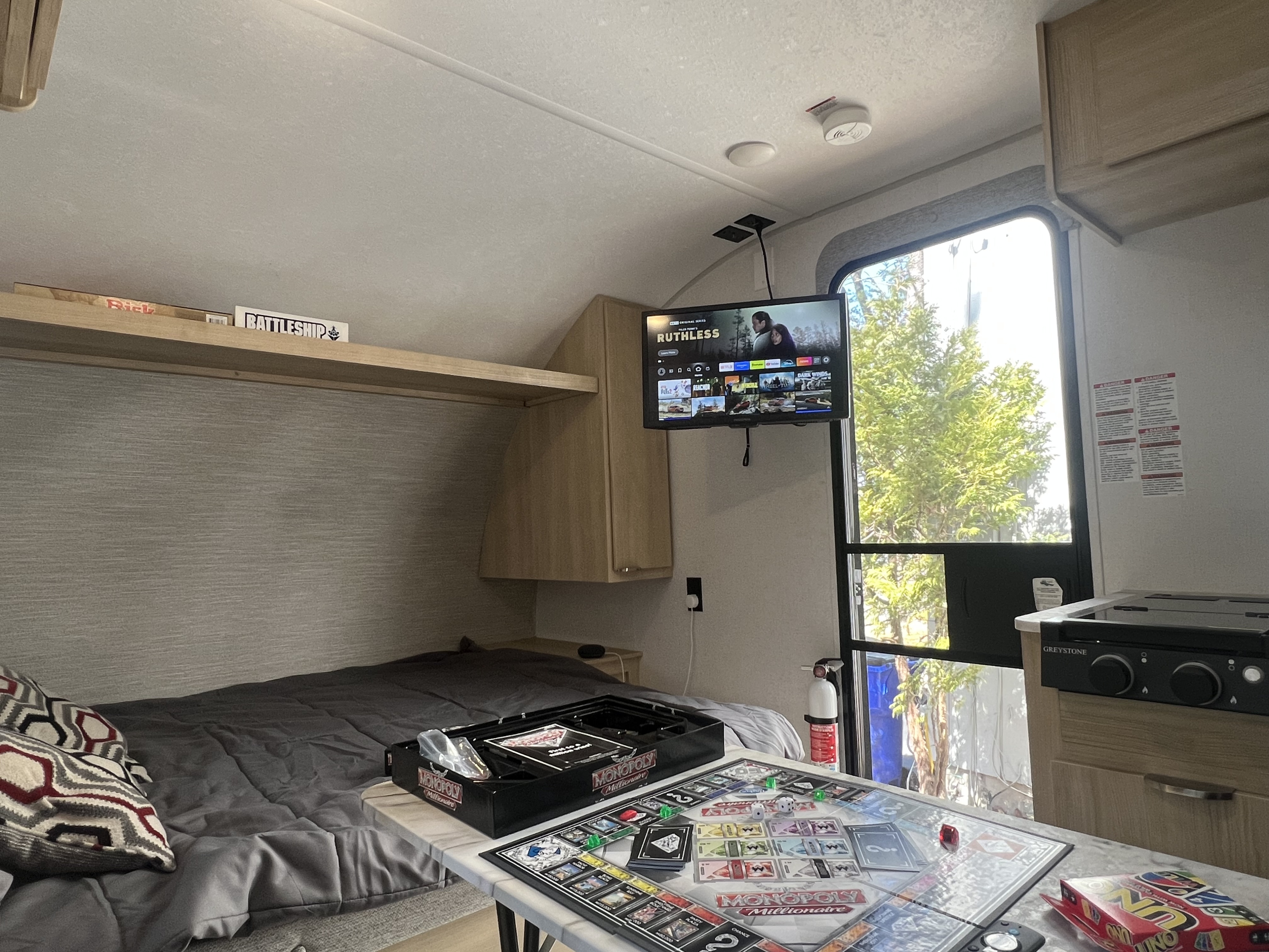 Cozy RV rental interior with board games (Monopoly, Battleship), TV, and compact kitchen.. Forest River Salem 2024
