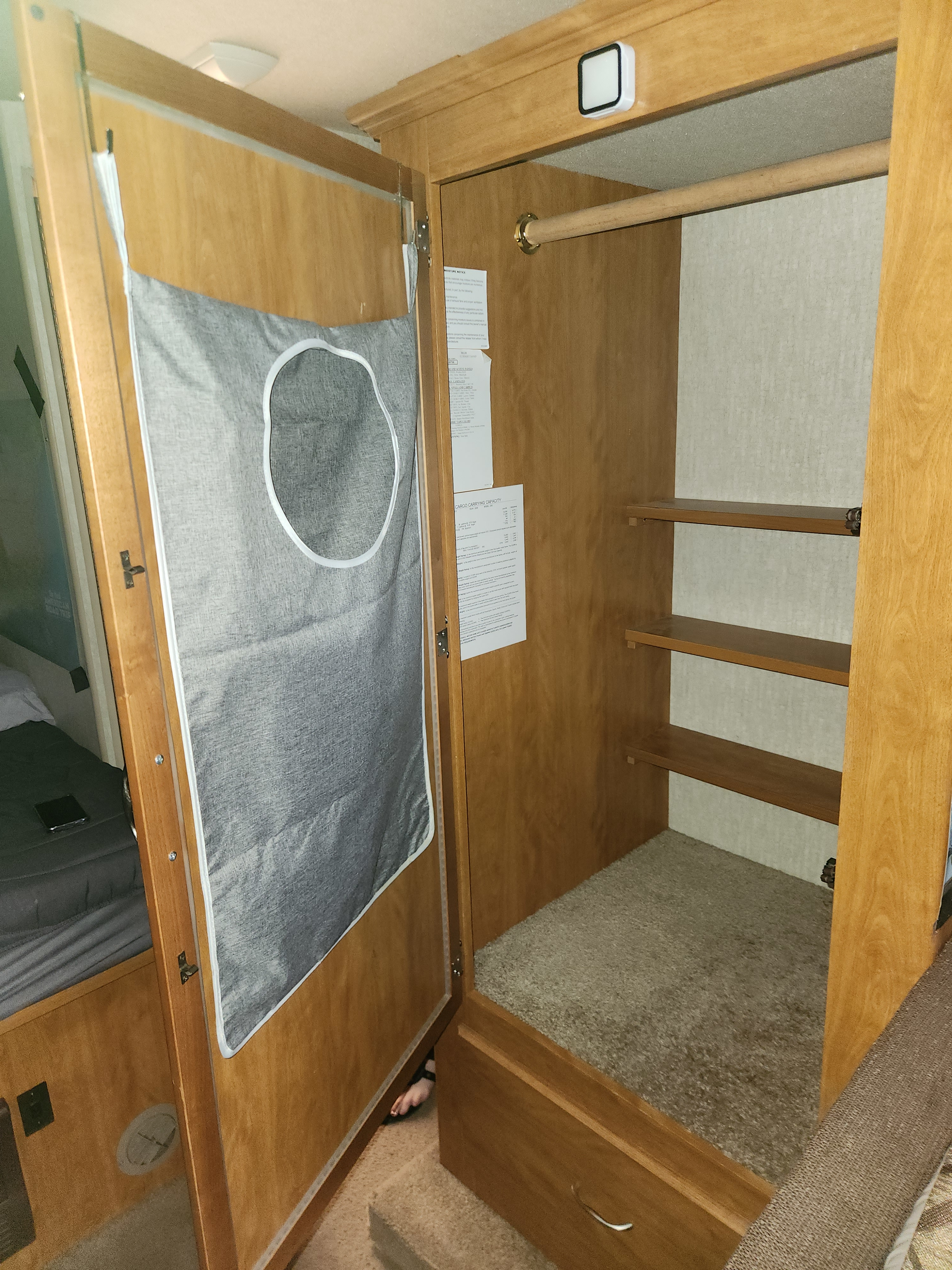 Inside an rv rental: a wood-toned closet with shelves, hanging rod, and a grey fabric laundry bag on the door. Carpeted floor visible.. Tioga Ranger 2008