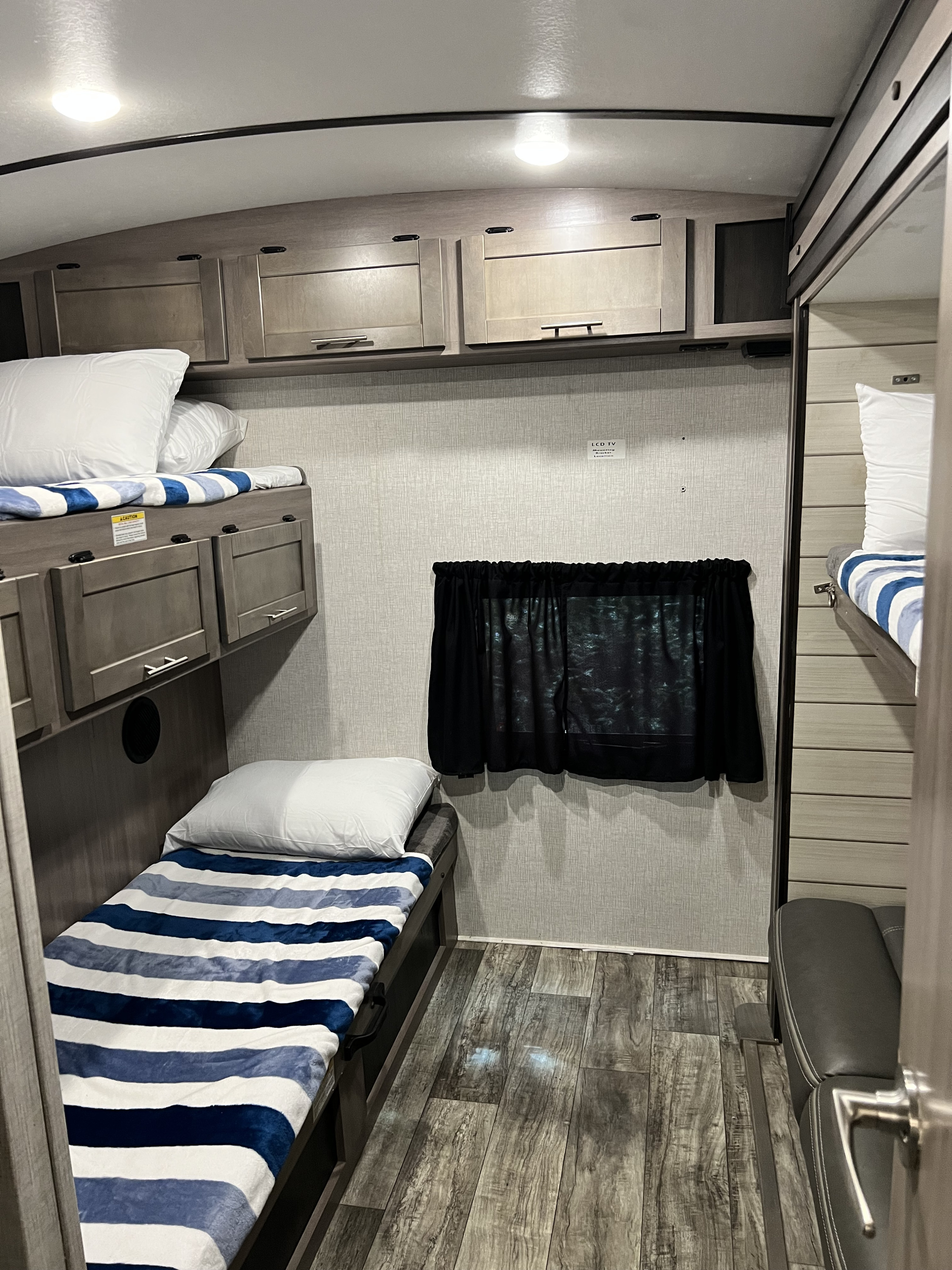 Cozy RV rental interior featuring bunk beds with striped bedding, overhead storage, and a practical living space.. Crossroads RV Sunset Trail Super Lite 2021