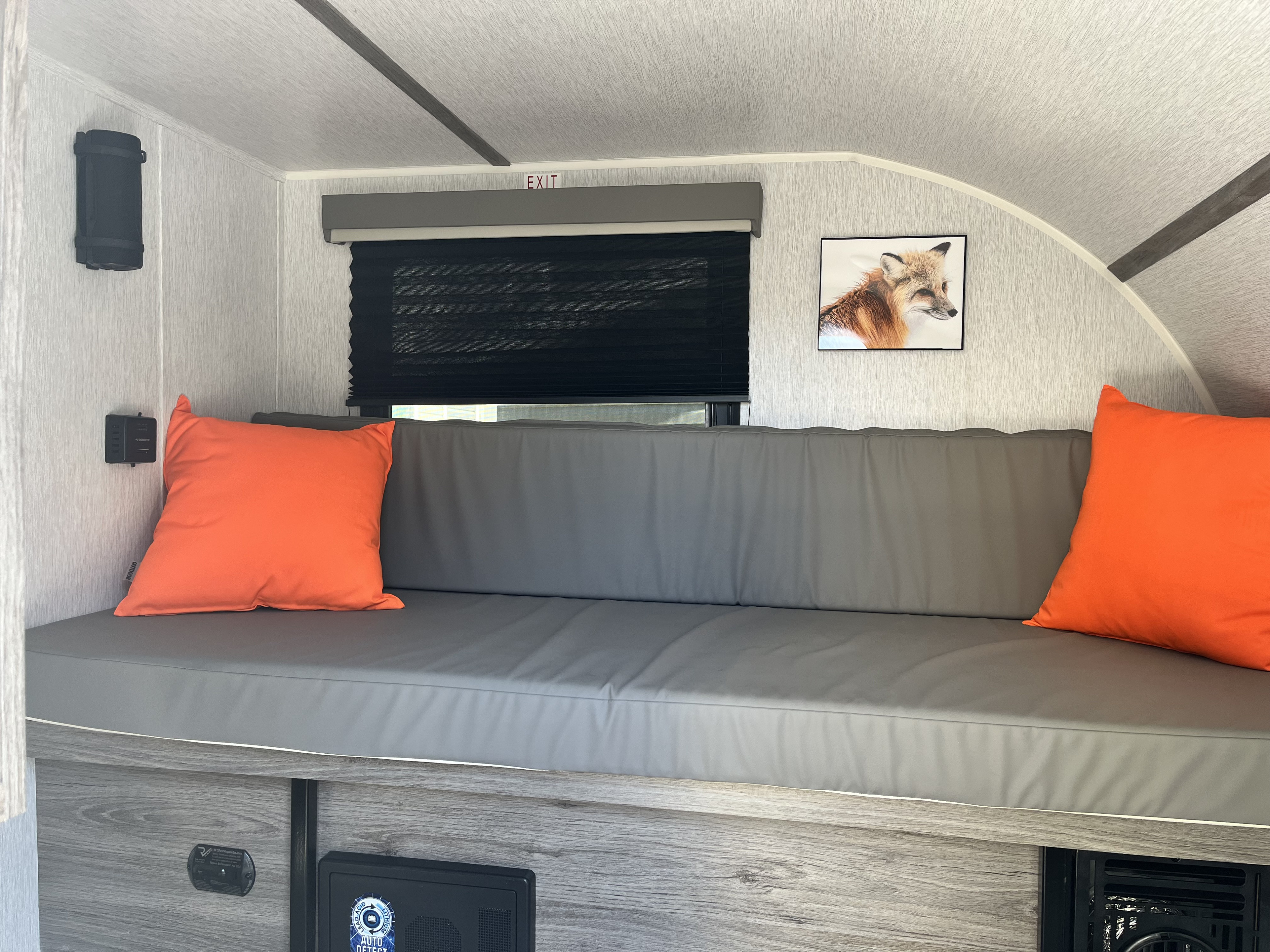 Cozy RV rental interior with a long gray bench seat, bright orange pillows, and a charming fox picture.. Sunset Sunray 109 sport 2025