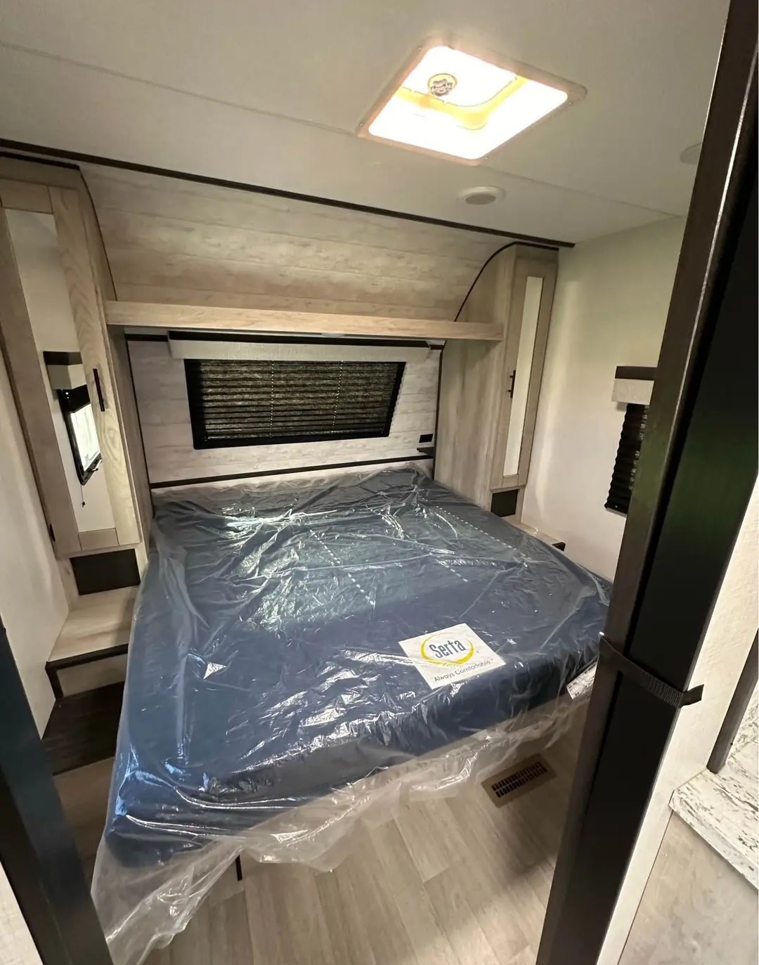 Cozy RV rental bedroom with a new Serta mattress (still plastic-wrapped), modern light wood interior, skylight, and ample storage.. KZ Connect C251BHK 2023