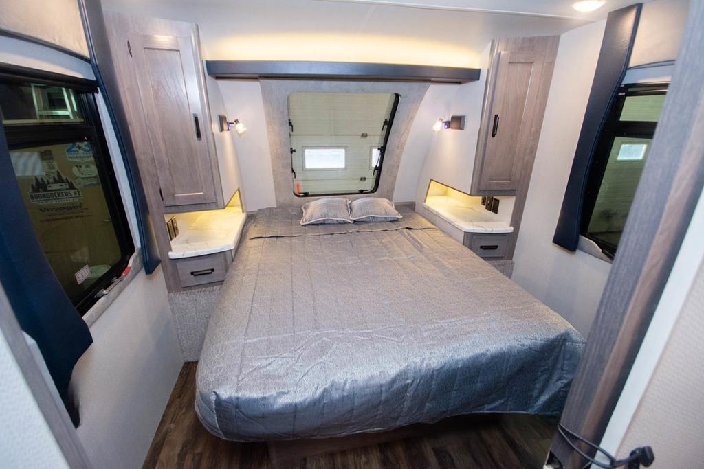 Spacious RV rental bedroom with grey bed, wood cabinets, reading lights, and window, offering cozy travel accommodation.. Lance Manufacturing Lance Manufacturing Trailer 2021