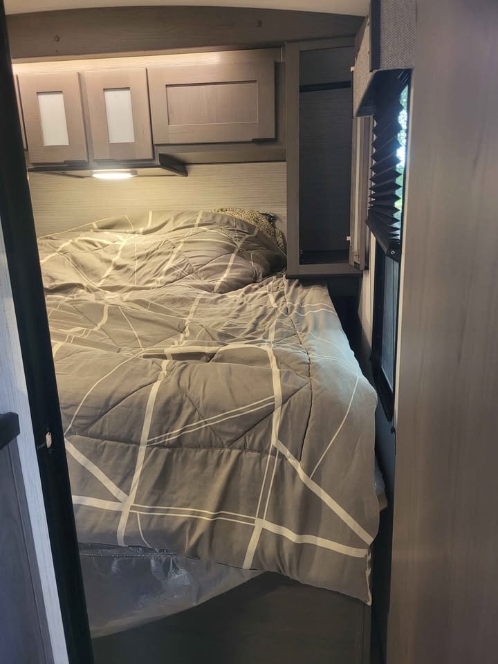 Inside an RV rental bedroom with a comfortable bed, overhead cabinets, and window. Ideal for your next adventure.. Heartland Mpg cruiser 2022