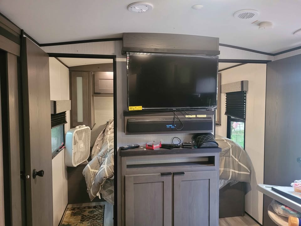 RV rental interior: A modern camper's living area featuring a large TV, soundbar, and a glimpse into the cozy bedroom.. Heartland Mpg cruiser 2022