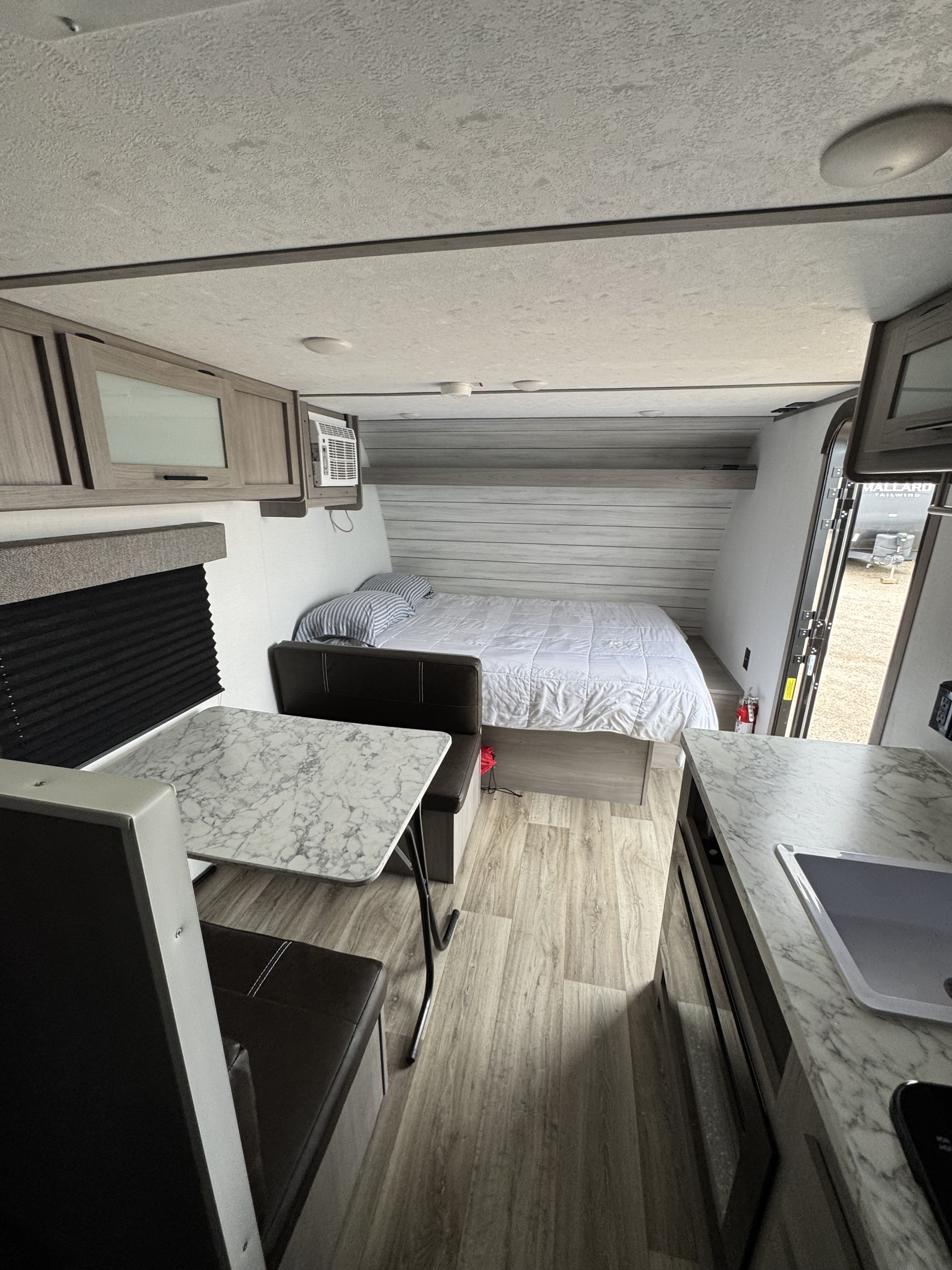 Inside this modern rv rental, a compact and comfortable living space features a bed, dinette, and kitchen. Perfect travel trailer interior.. Coleman Lantern LT 2023