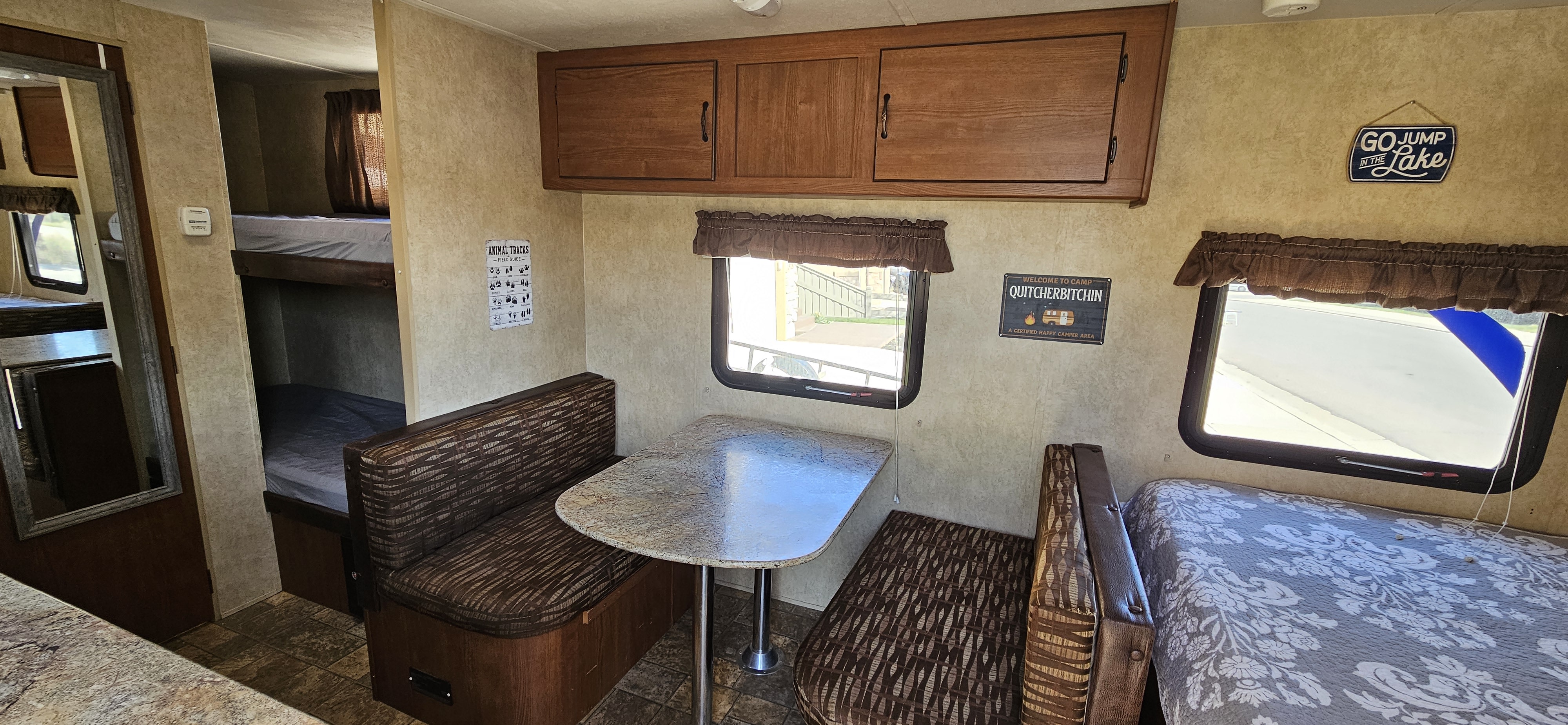 RV rental interior features a dinette, bunk beds, and main bed, decorated with camp signs.. Forest River Salem Cruise Lite 2015