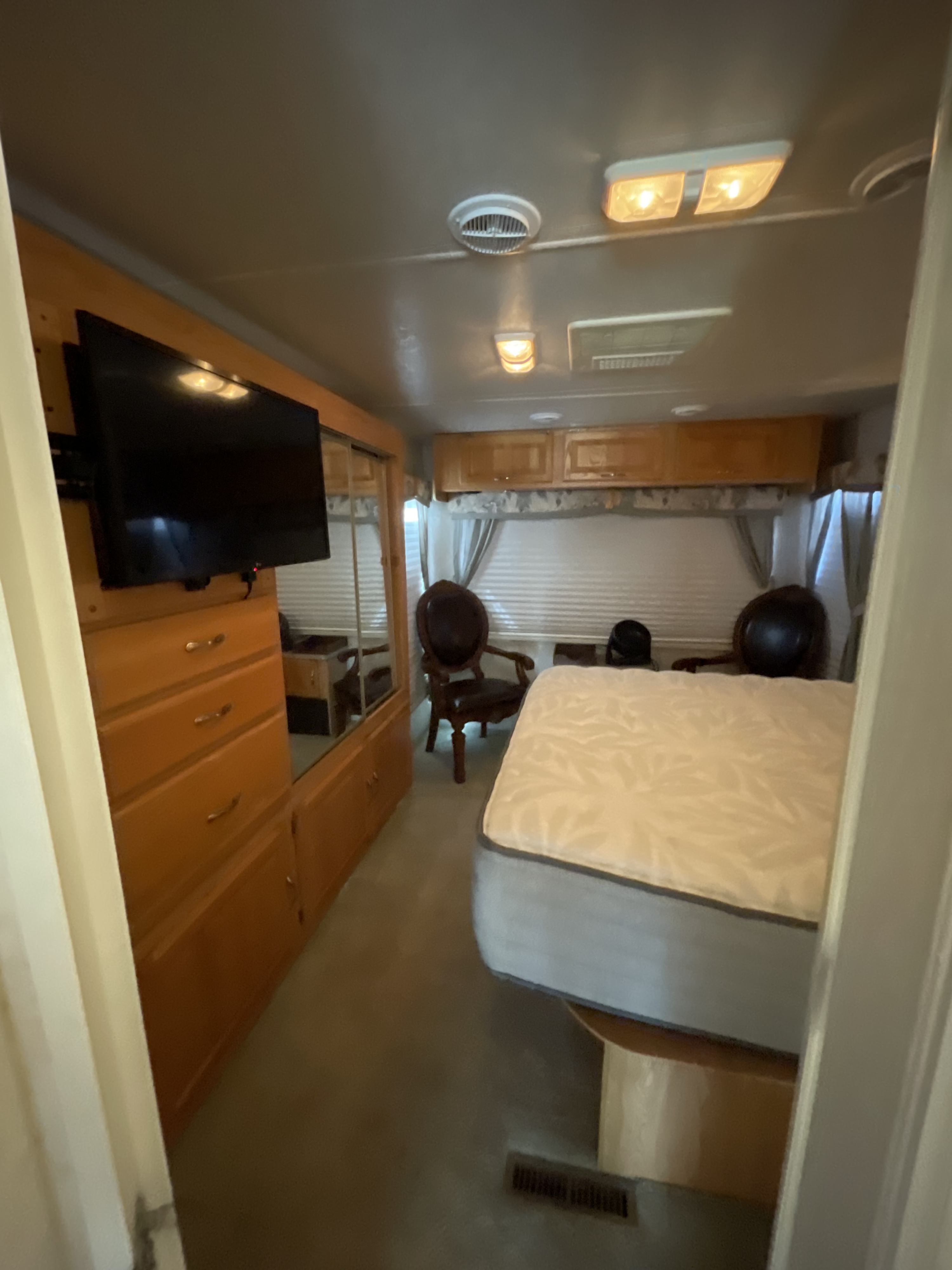 RV rental bedroom: comfortable bed, wall-mounted TV, wood cabinets, mirror, and ample space for travel.. R-Vision Condor 2004