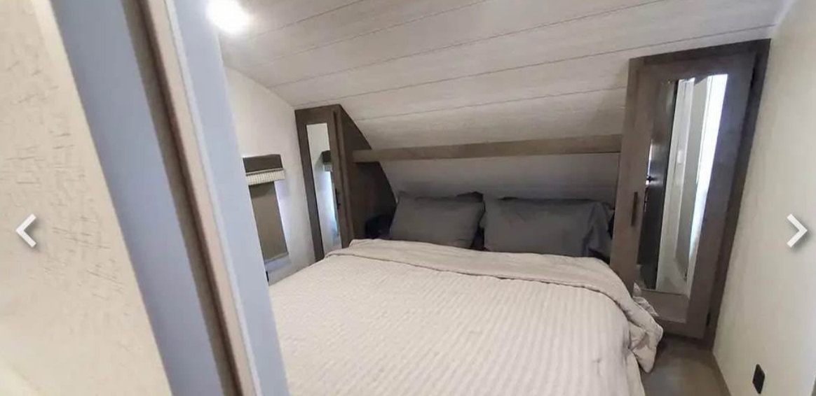 Cozy RV rental bedroom featuring a bed, mirrored wardrobes, and shiplap ceiling details.. Forest River Cruise Lite 2022