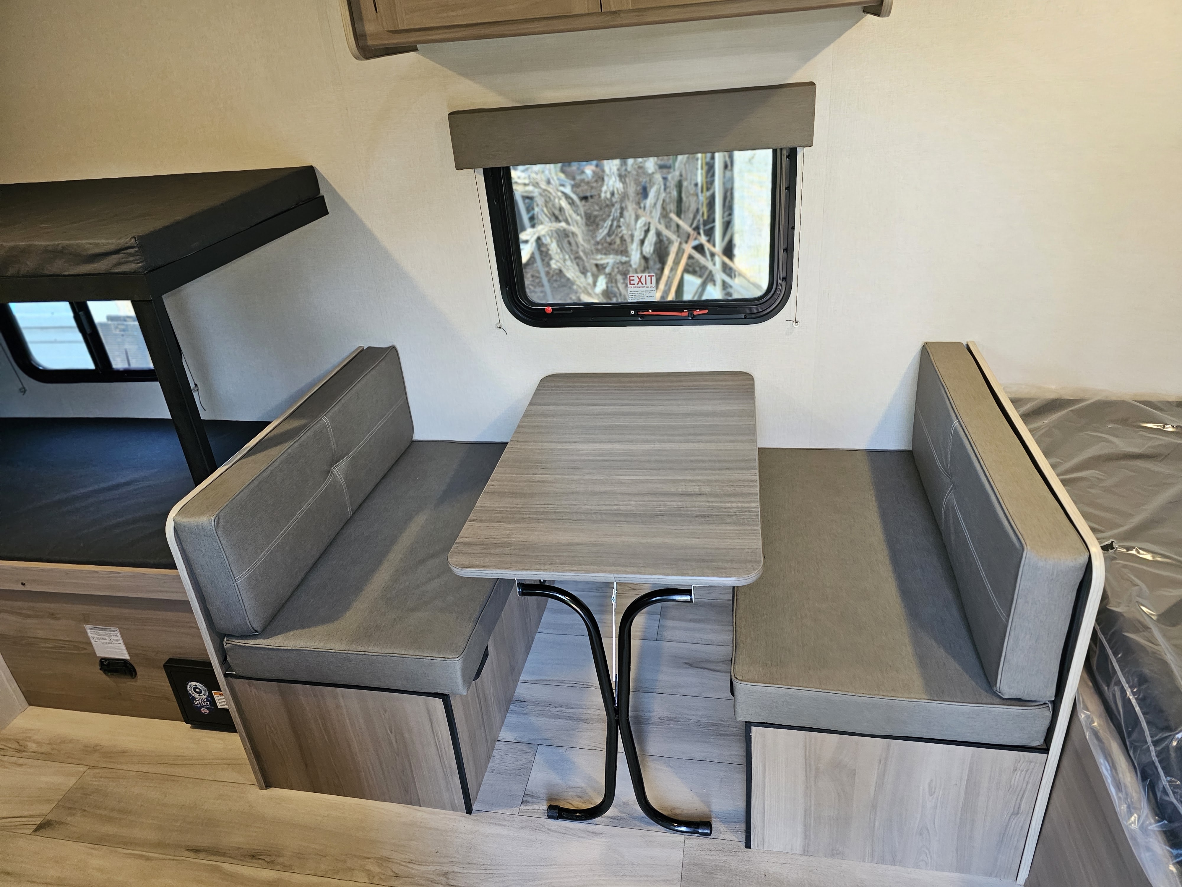 Inside this rv rental: dinette with table & bench seating, bunk bed, and emergency exit window.. Keystone Coleman 17BX 2025