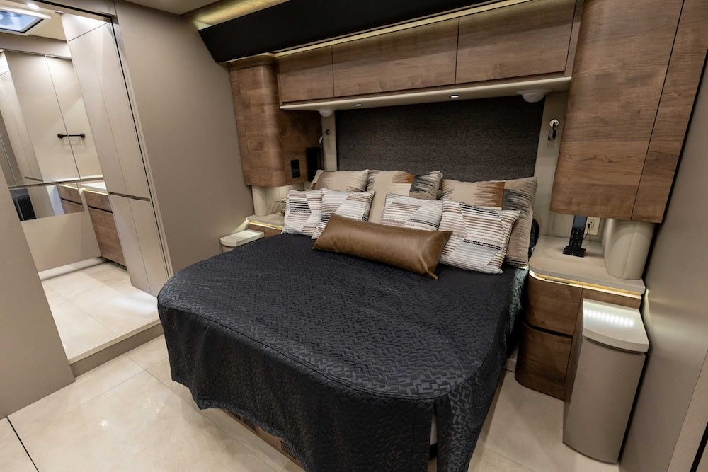Experience ultimate comfort in this luxurious RV rental bedroom, featuring elegant decor, a large bed, and smart storage.. Newell Coach P50 2024