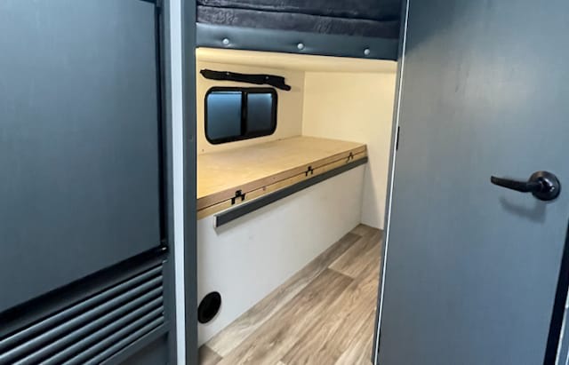 RV rental interior featuring a convertible bunk bed with a window, ideal for compact camper sleeping and travel.. Keystone Bullet 2022