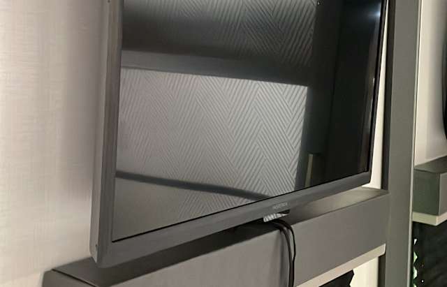 A wall-mounted TV and entertainment shelf in an RV rental, compact for road trips. Note the patterned wall.. Keystone Bullet 2022
