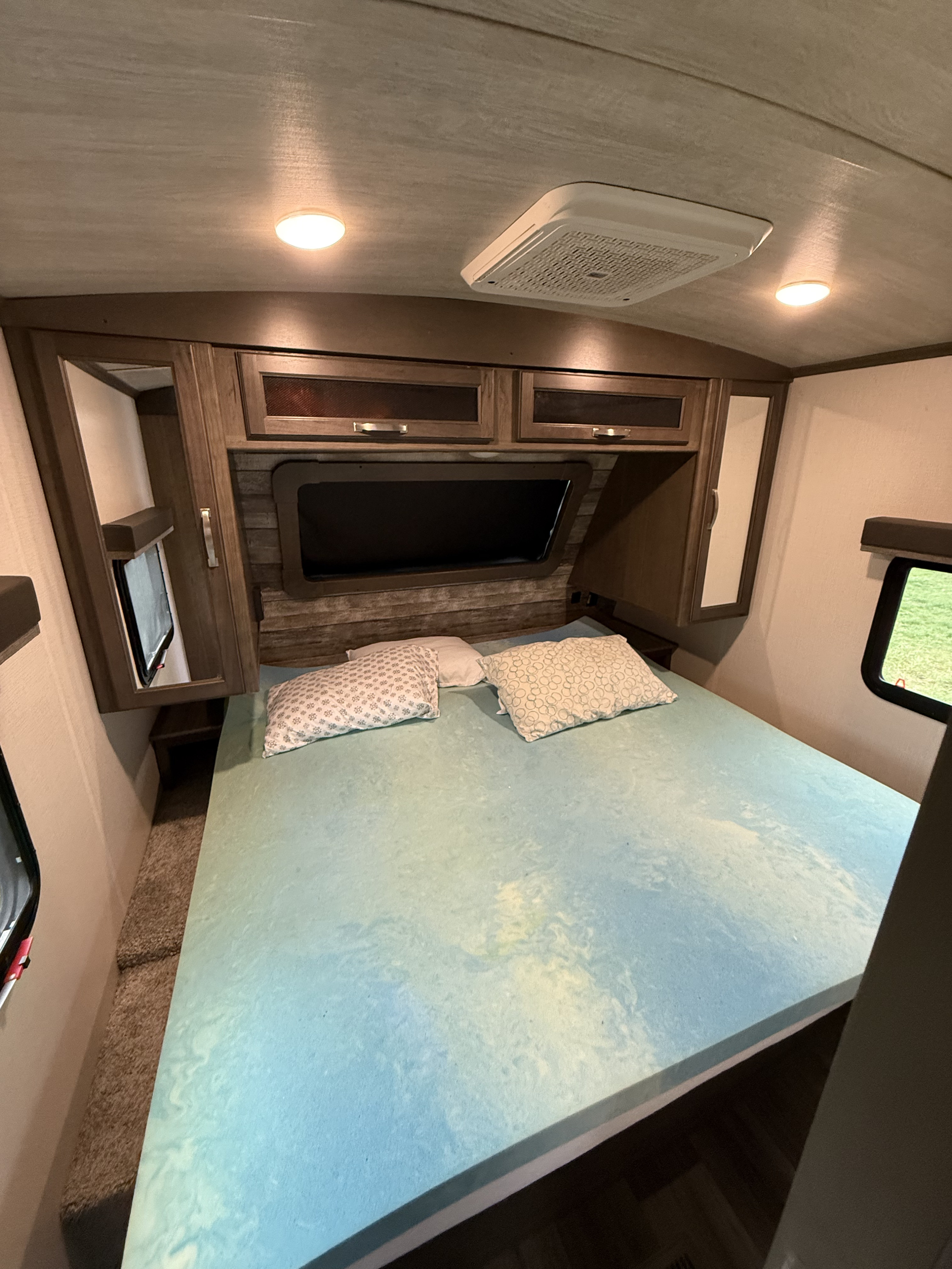 Cozy RV rental bedroom with spacious bed, built-in storage, and windows for your next adventure.. Keystone RV Cougar 2022