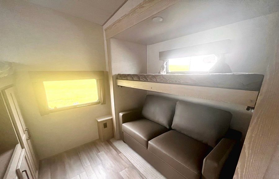 RV rental interior: bunk bed over a sofa, bright window to the left. A cozy, functional living space.. Forest River Flagstaff Super Lite 2023
