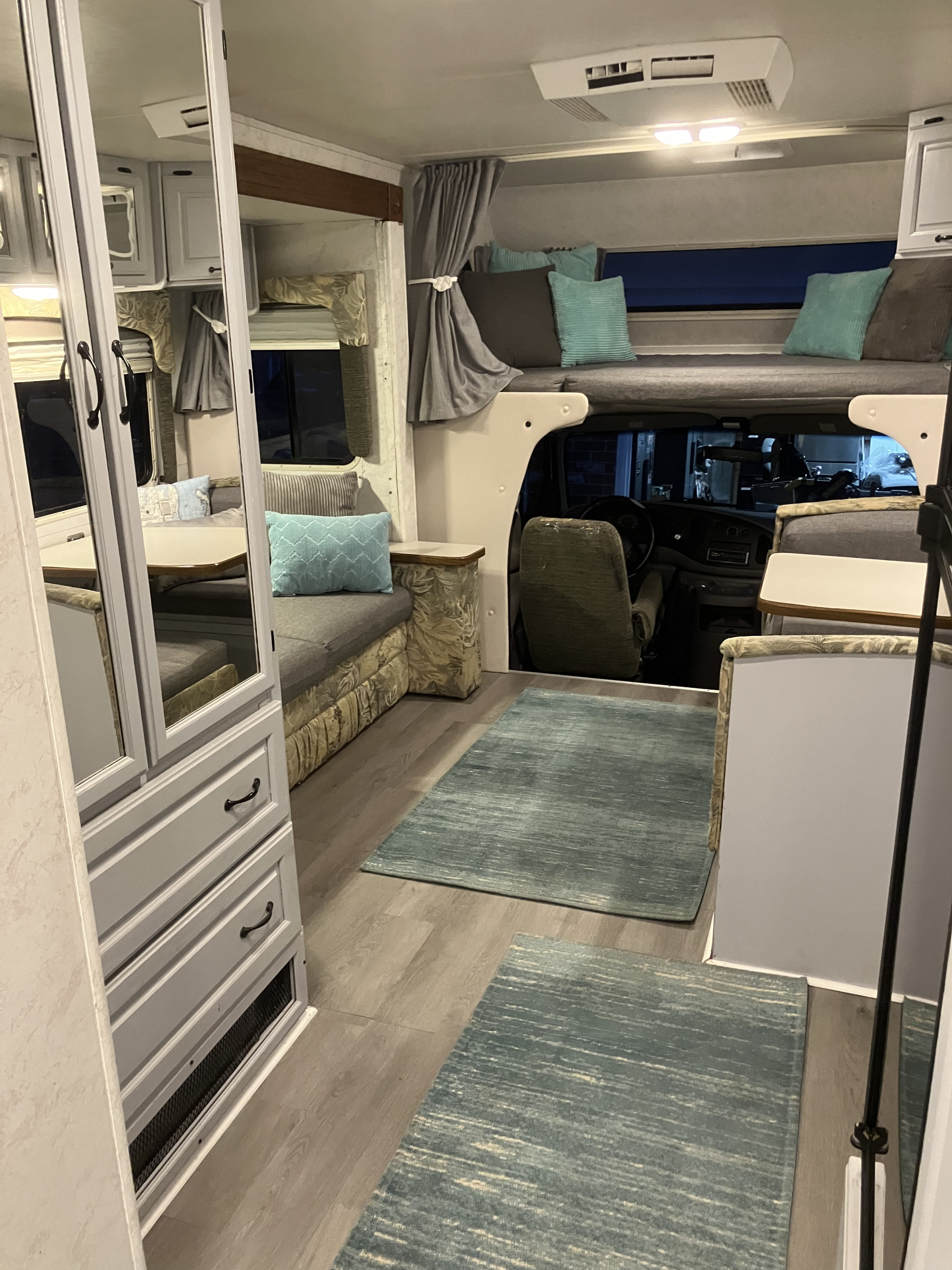 Cozy RV rental interior featuring a living area, overhead bed, and cockpit view, ideal for travel adventures.. Dutchmen Other 2001