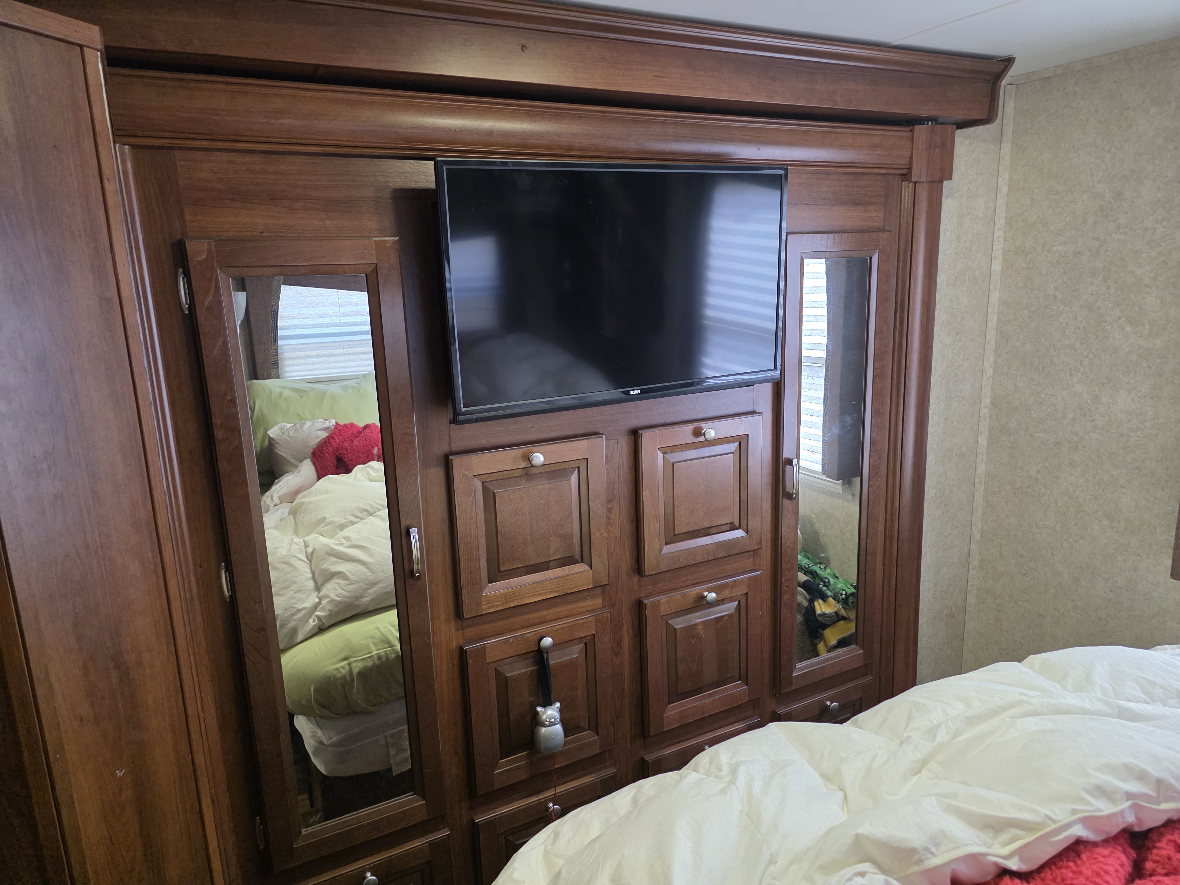 RV rental bedroom: a built-in wooden cabinet with a TV, mirrored wardrobe doors reflecting the bed, and storage.. Georgetown Georgetown Motorhome 2014