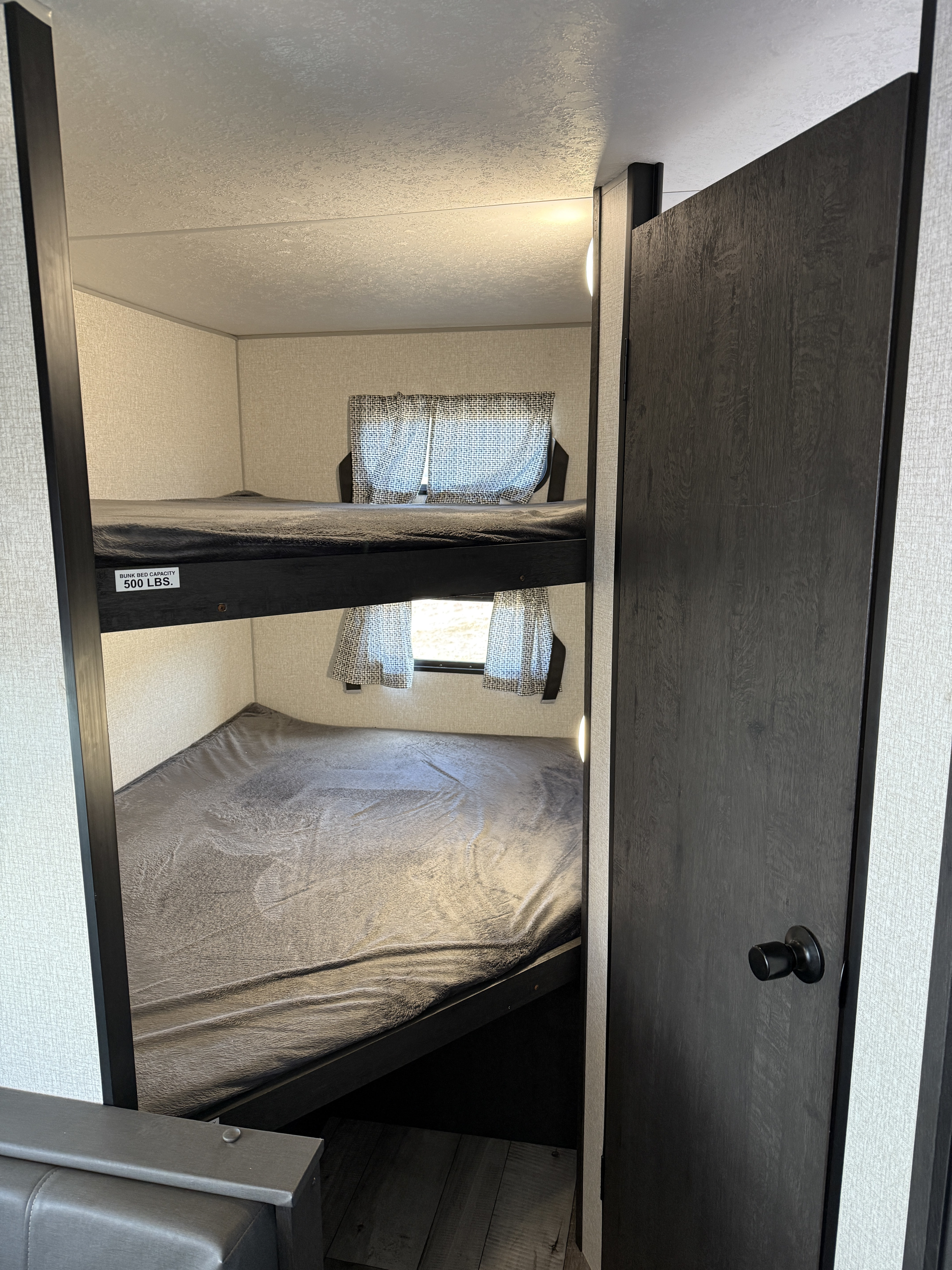 This RV rental bunk area offers two beds, each rated for 500 lbs, with bright windows and sleek interior design.. Sportsmen SE 2022